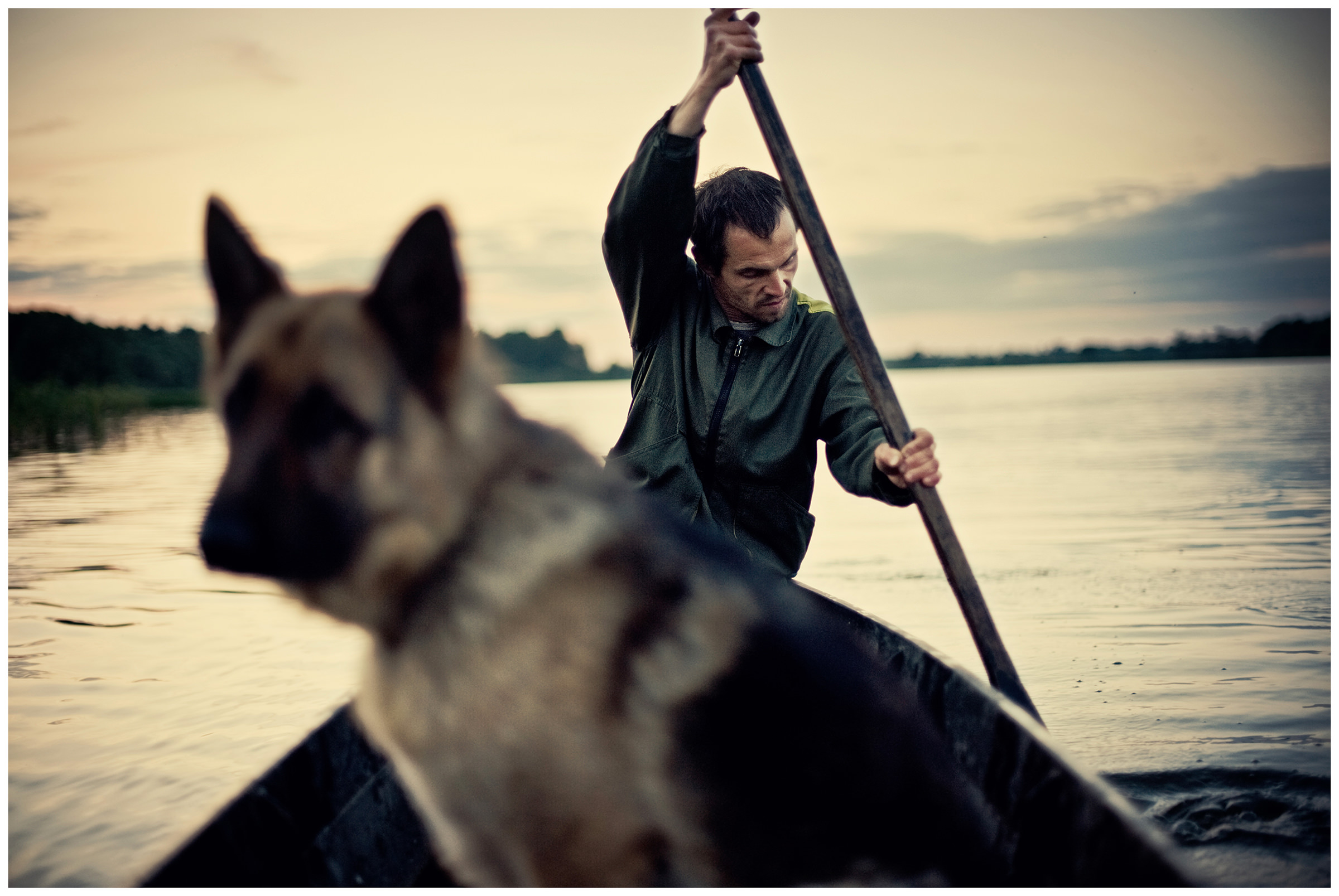 Belarus, village of Chereshlja. A man with a dog sitting in a boat.