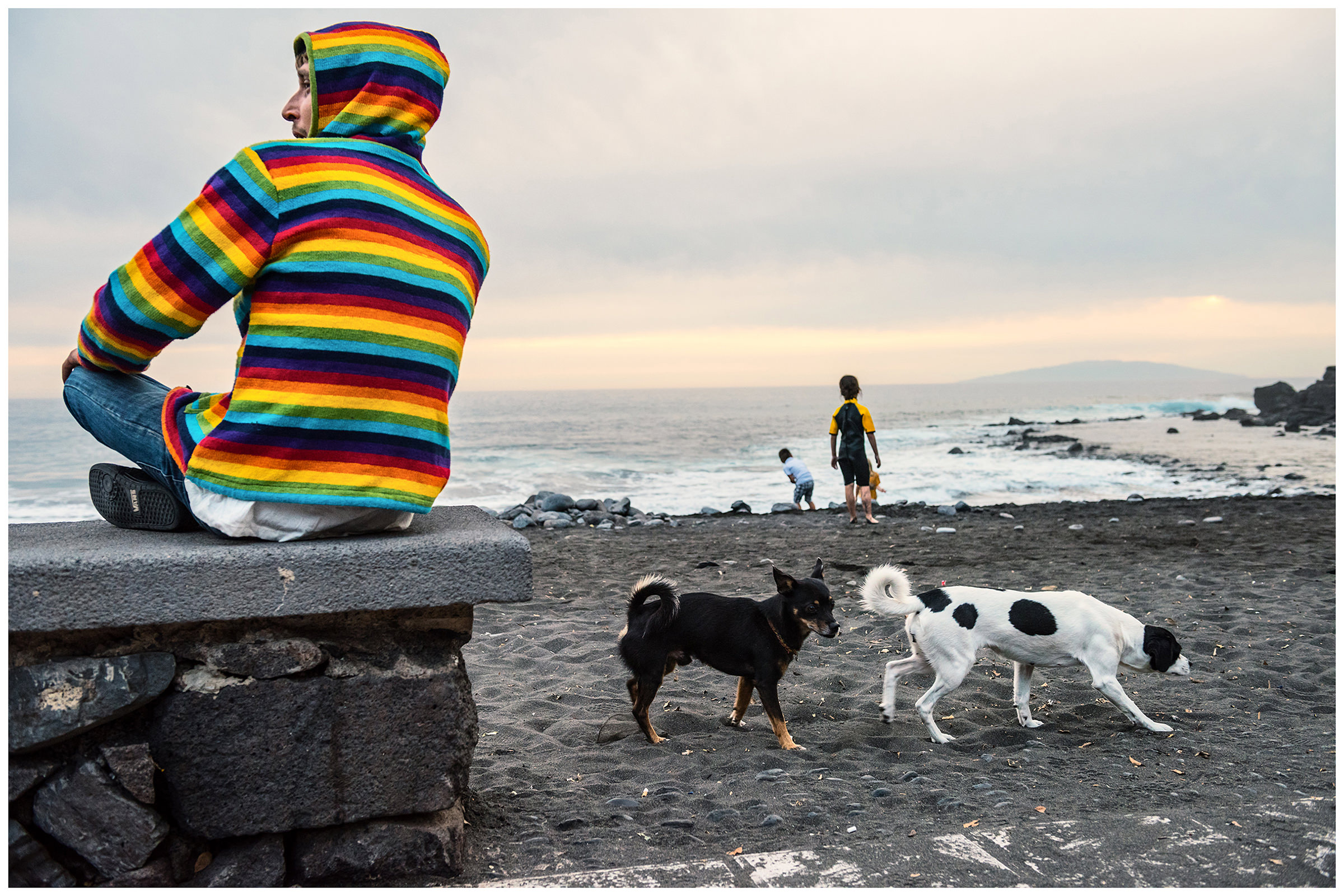 Valle Gran Rey, La Gomera, Canary Islands, Spain. A man sits at the beach promenade of Valle Gran Rey at sunset.