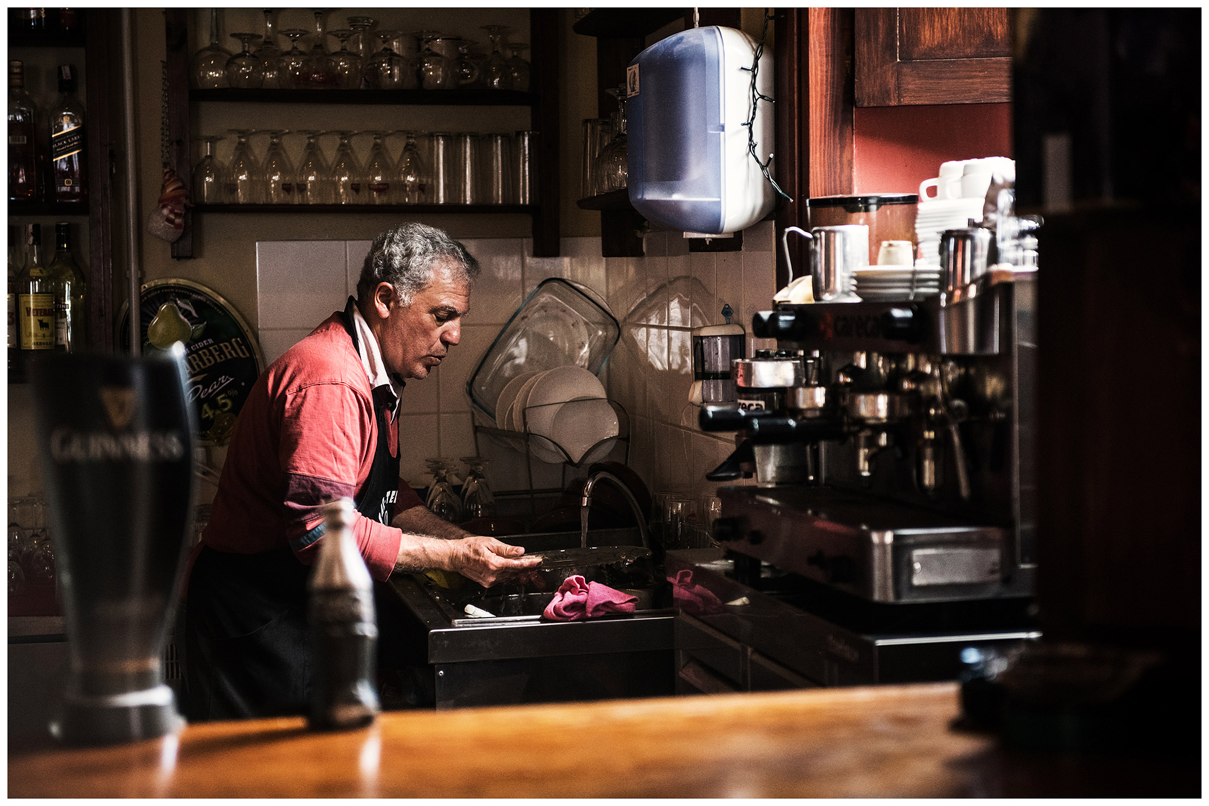 Hermigua, La Gomera, Canary Islands, Spain. The owner of Caffee La Casa Creativa, washes the dishes.