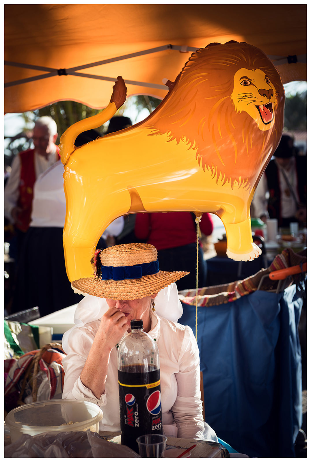 San Sebastian de la Gomera, La Gomera, Canary Islands, Spain. The inhabitants of the city of San Sebastian de la Gomera celebrate the city festival Romeria. A woman with a balloon sits at a table.