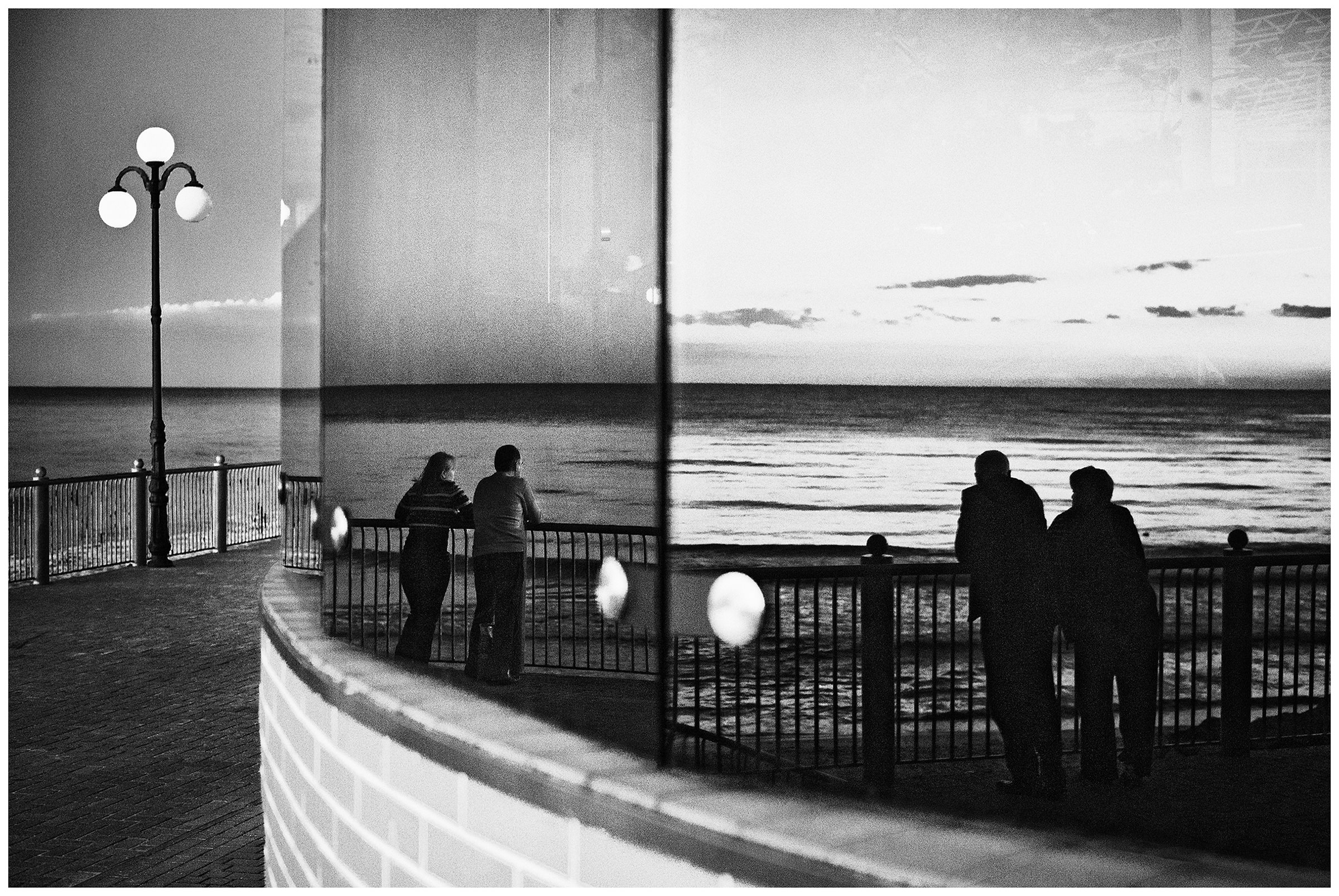 Kaliningrad, Russia. A couple reflected in the windows of a building in Svetlogorsk.
