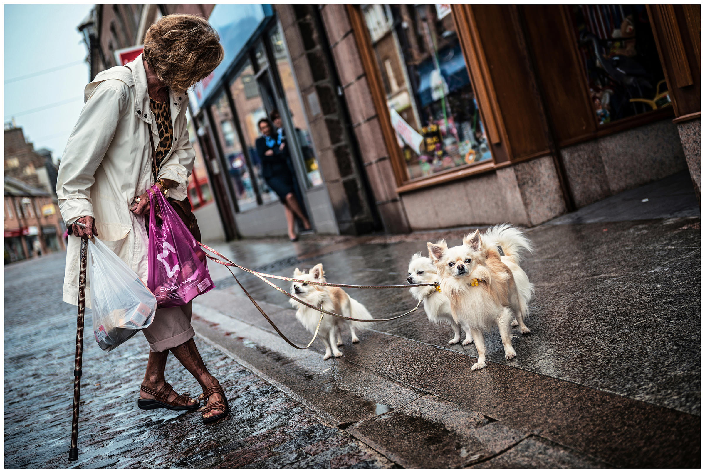 Scotland, Peterhead A woman stands on the street with her three dogs.