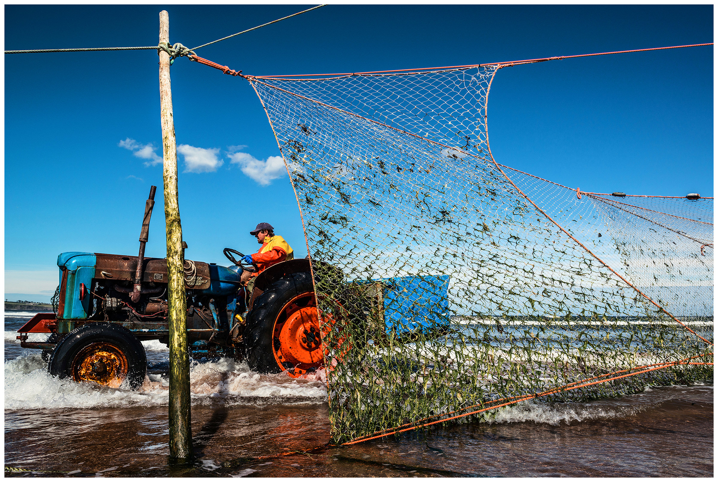 Scotland, Usan Montrose. A man with the tractor rides to repair fishing nets.