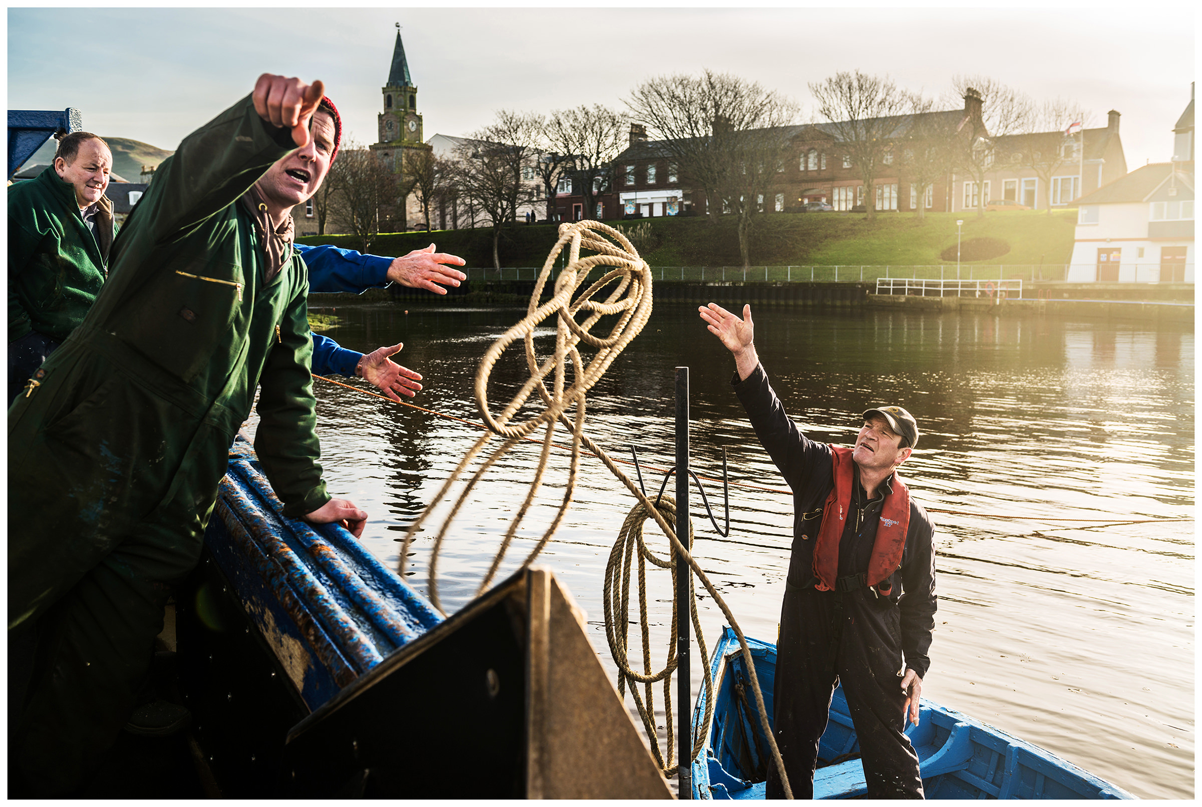 Scotland, Girvan, Ayrshire. A man on a boat throws his colleague a rope. The family business "Alexander Noble and Sons Limited" was founded in 1946 and specialises in shipbuilding and the repair of fishing boats.