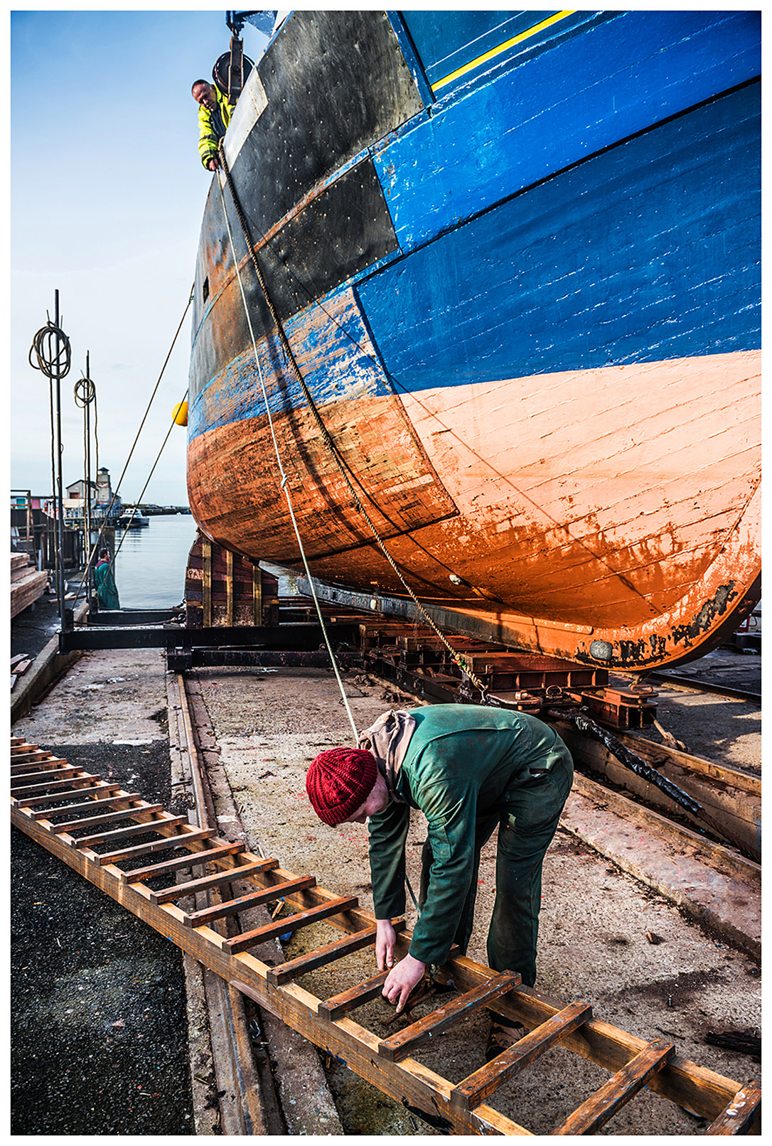 Scotland, Peterhead. A man with a ladder is standing in front of a ship.