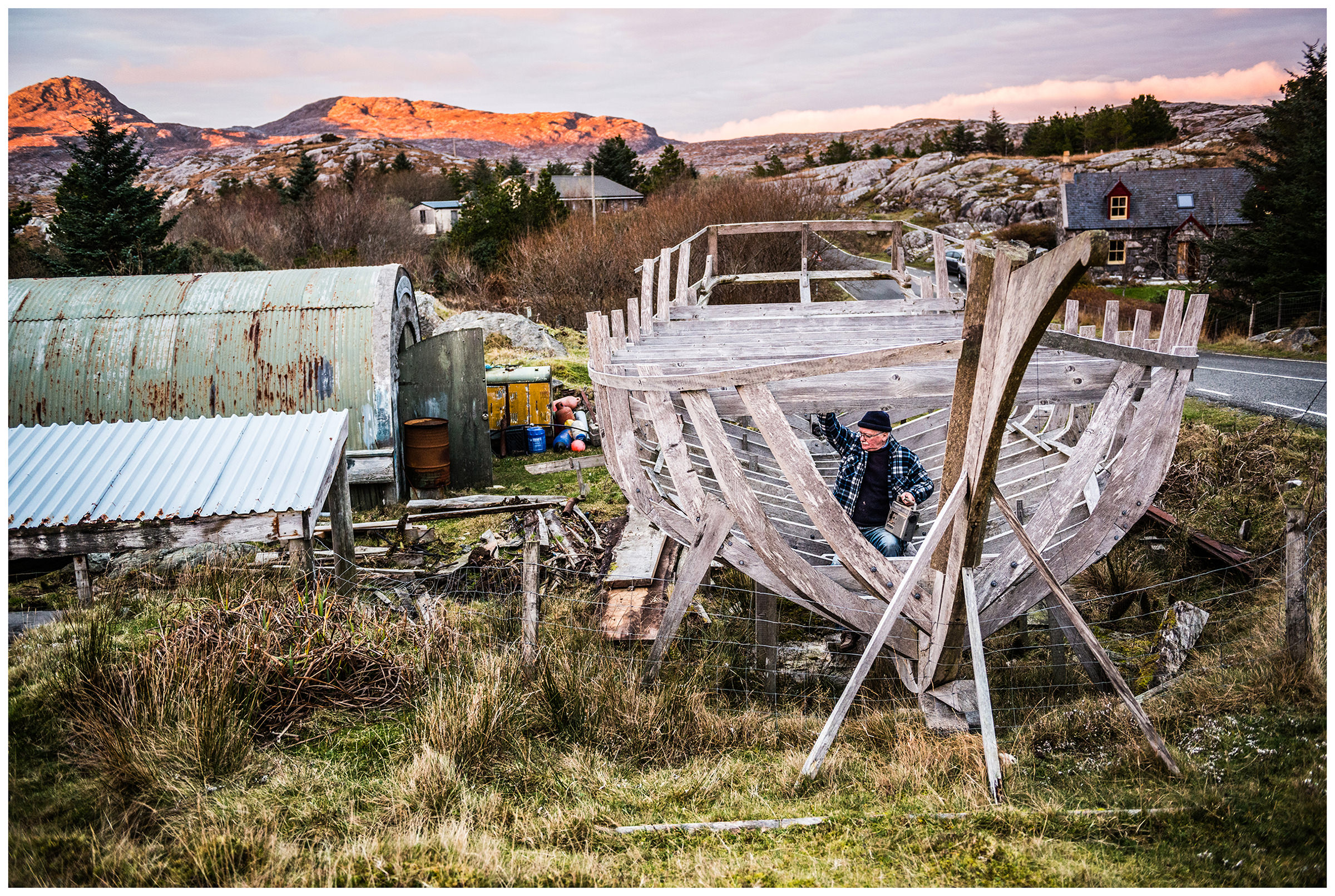 Scotland, Isle of Harris. John MacAulay, the most famous boat builder on Isle of Harris, sits in the scaffolding of his ship.