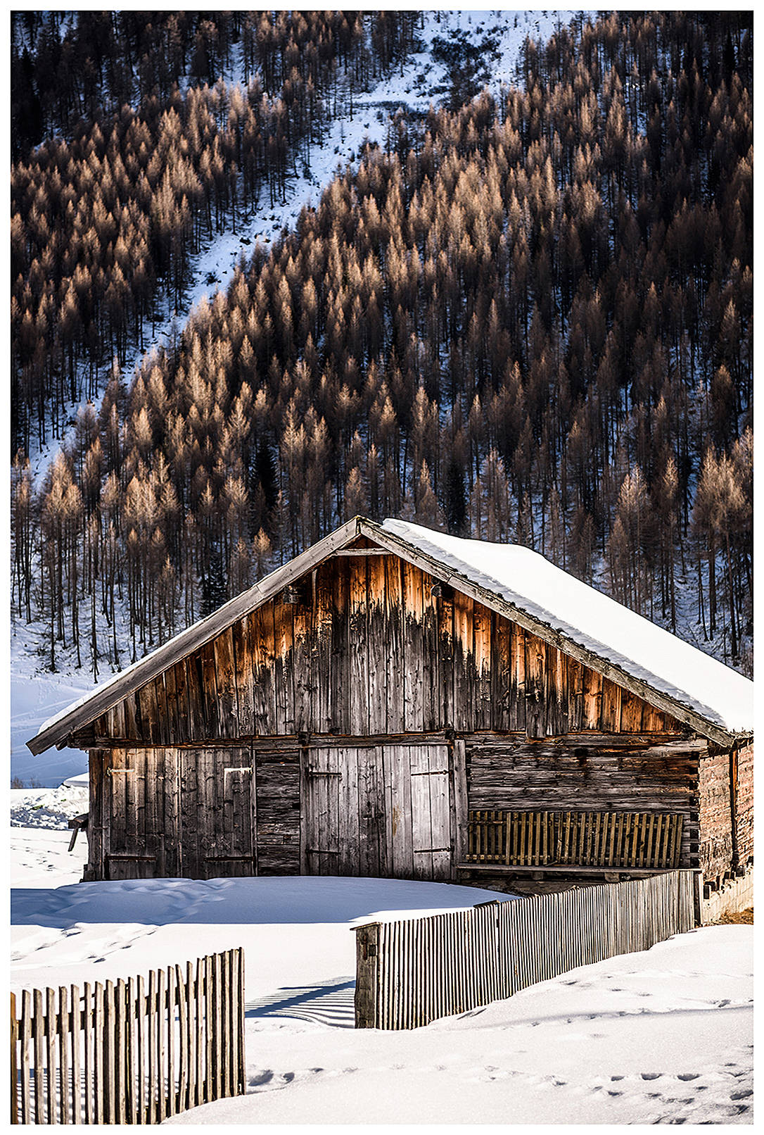 Kasern, Schmirntal, Wipptal, North Tyrol, Austria. A barn and a fence stand in the snow.