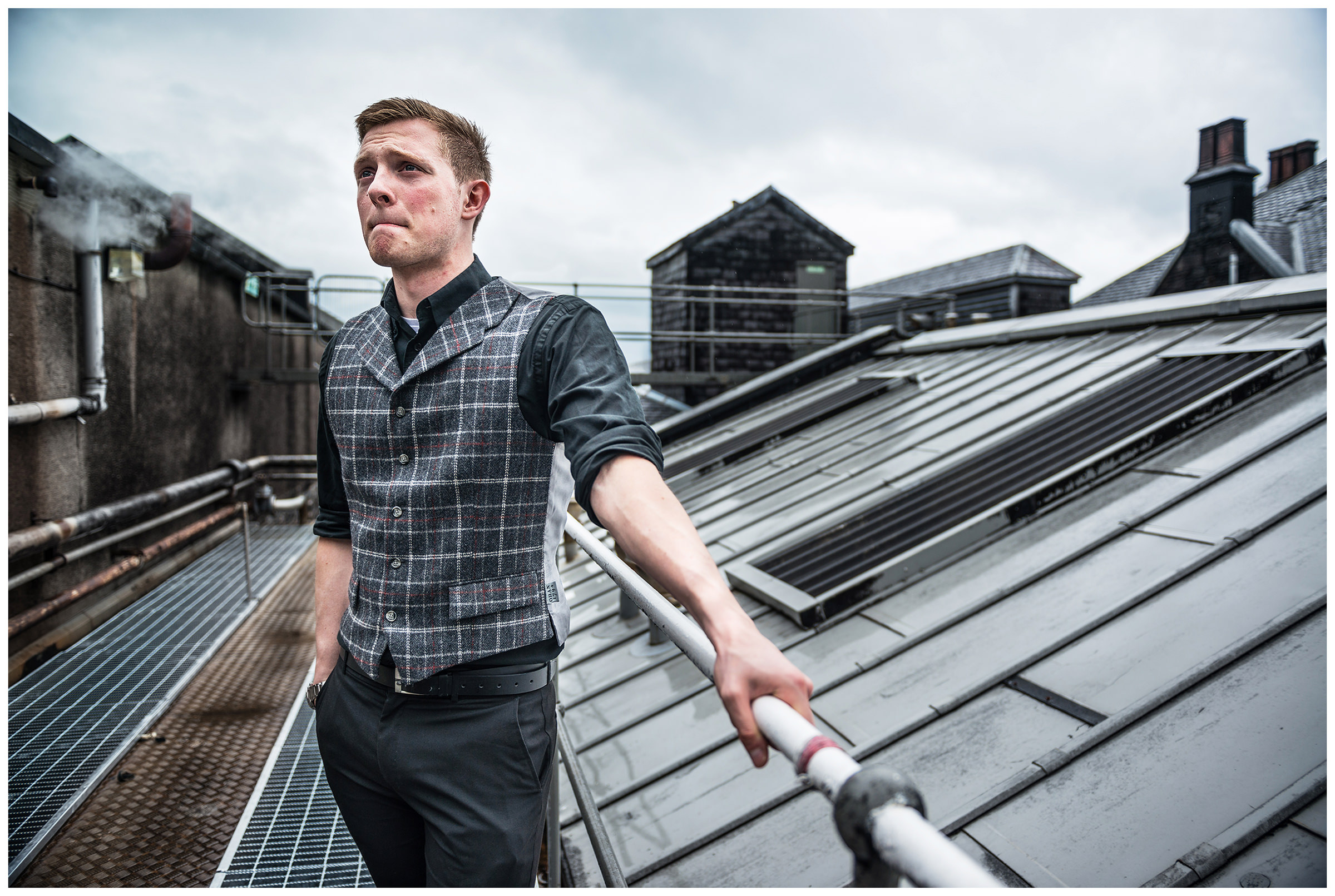 Scotland, Oban. A young man is standing on the roof of the wiskey distillery.