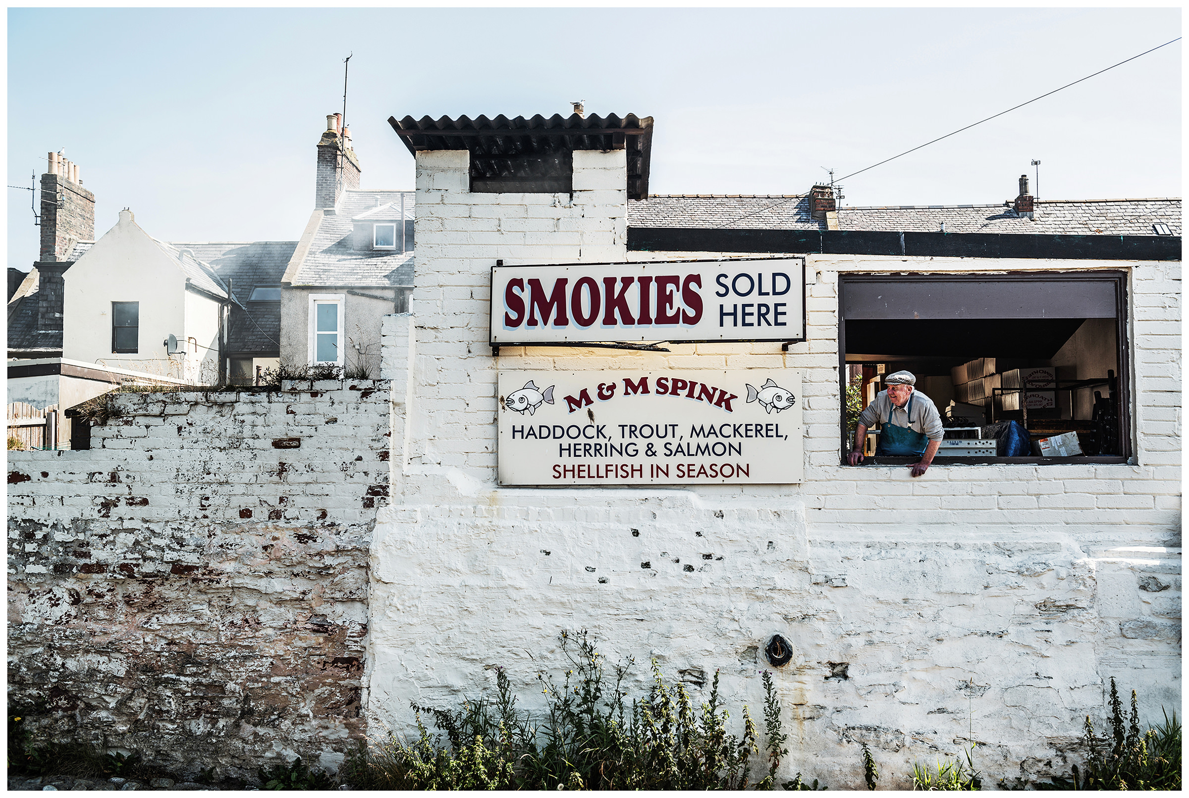 Scotland, Arbroath. A man looks out the window at his smokehouse.