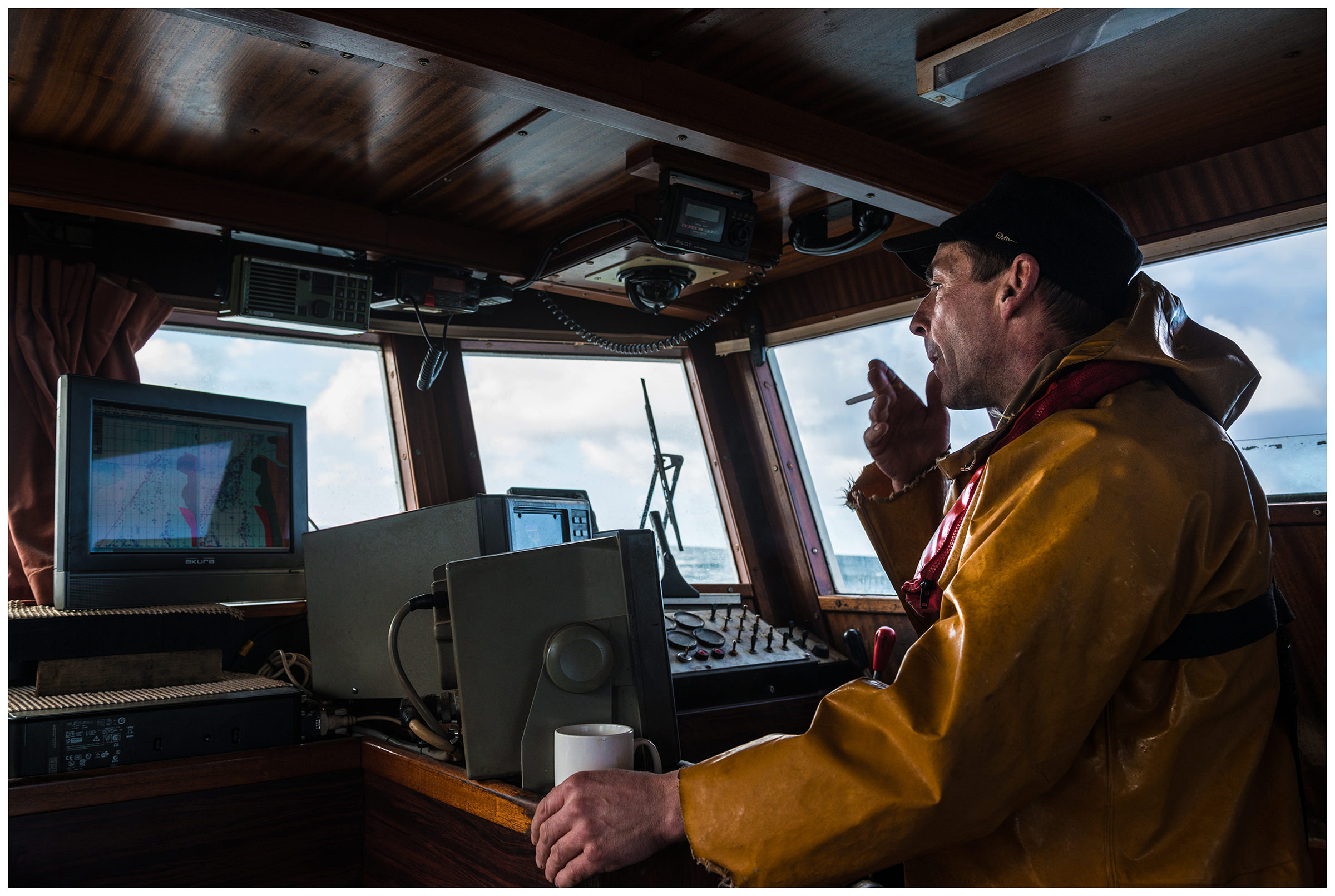 Scotland, Girvan. A crab fisherman smokes on board his ship.