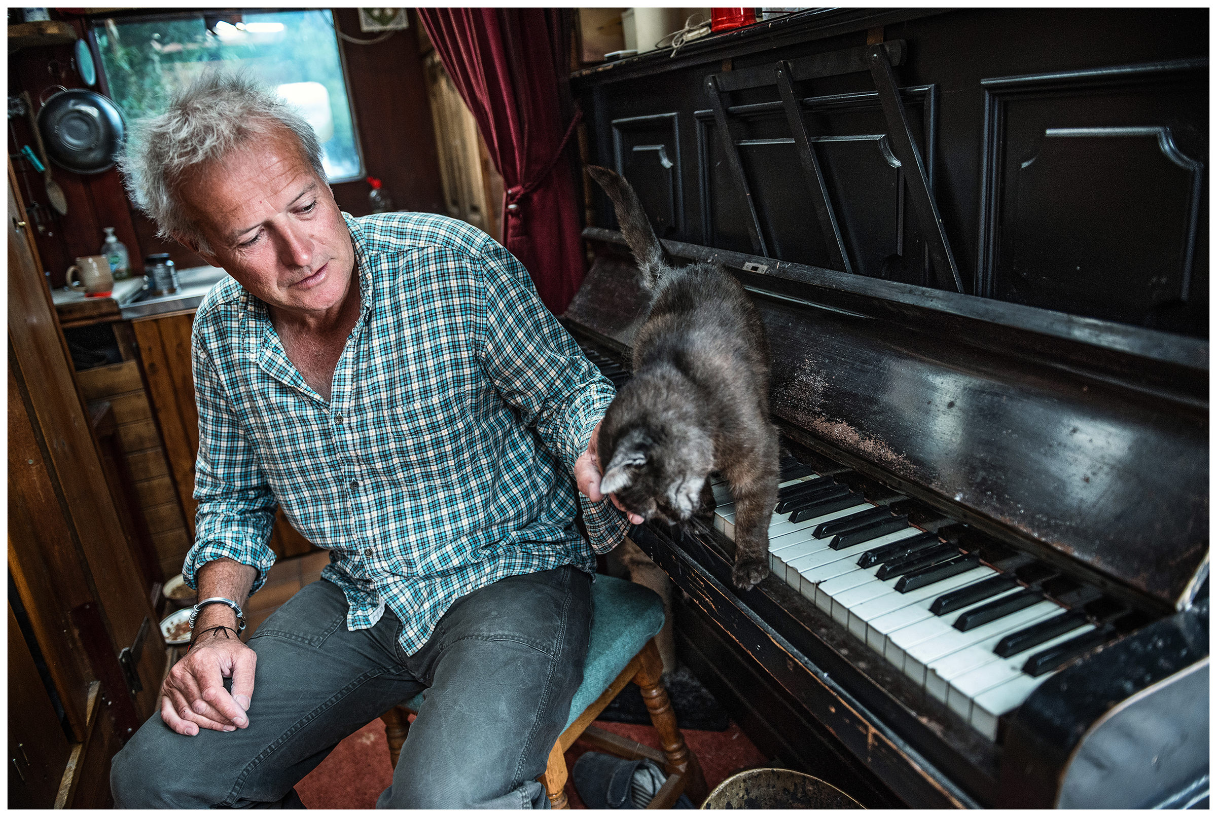 Scotland, Loch Ness. Nessy Hunter Steve Feltham spends all his time at Loch Ness Coast, where he has been living in a motorhome since 1991. He sits with his cat at a piano in his motorhome.