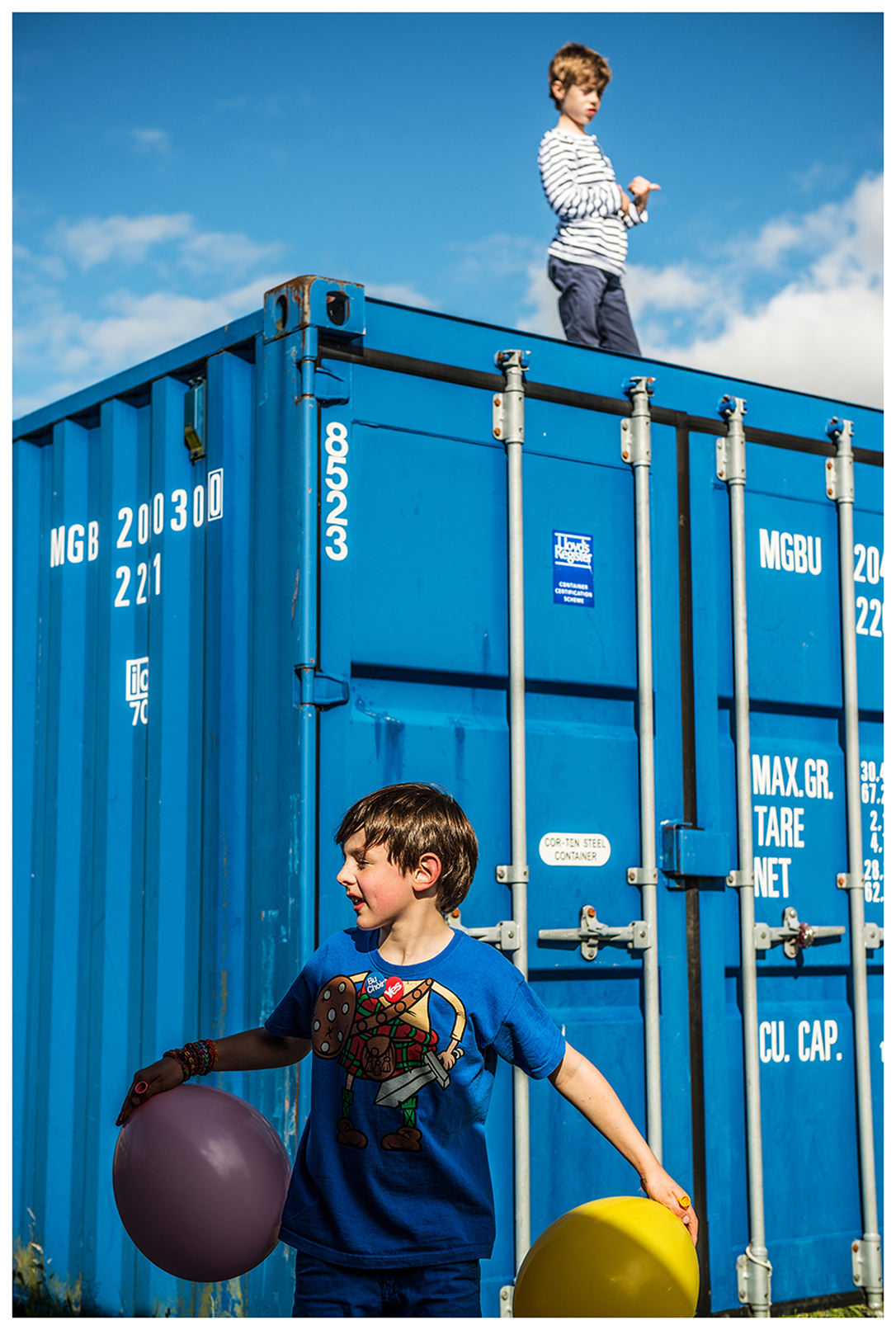 Scotland, Fort William. A boy with balloons is standing in front of a container.