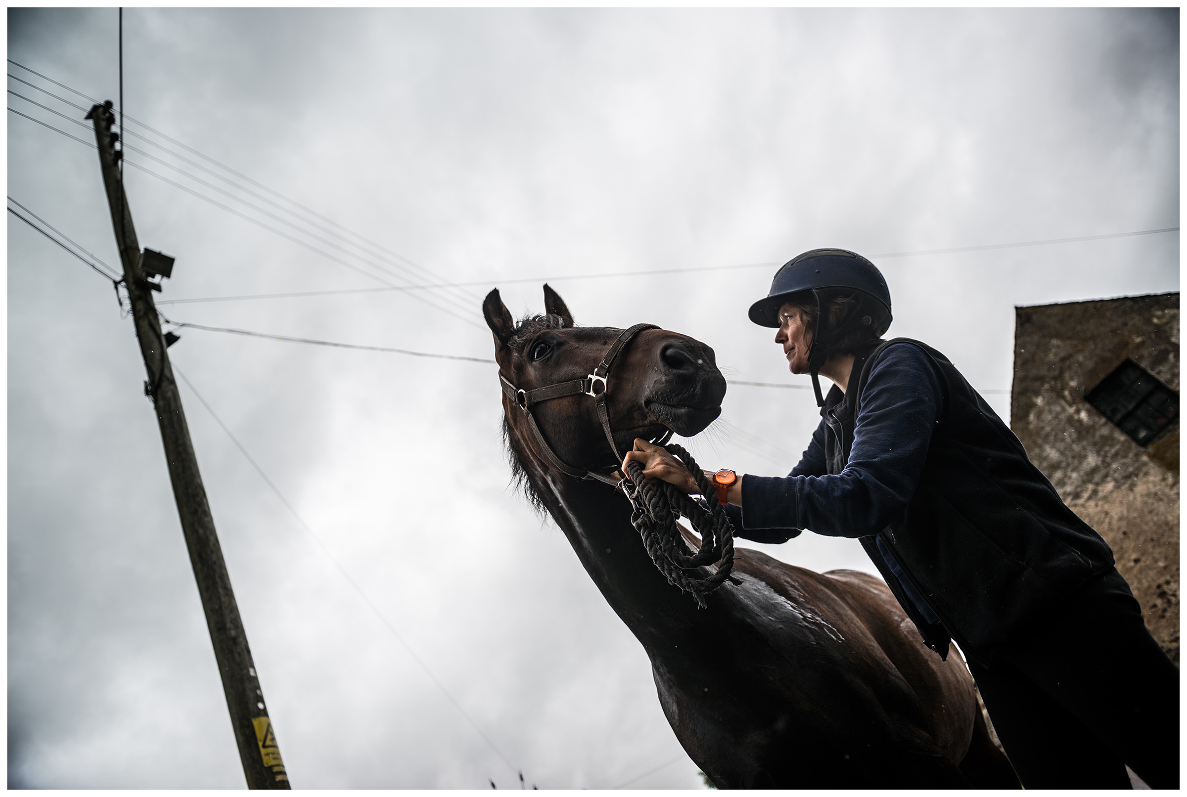 Schottland, Drumnadrochit Eine Frau steht mit einem Pferd unter dem Regen.