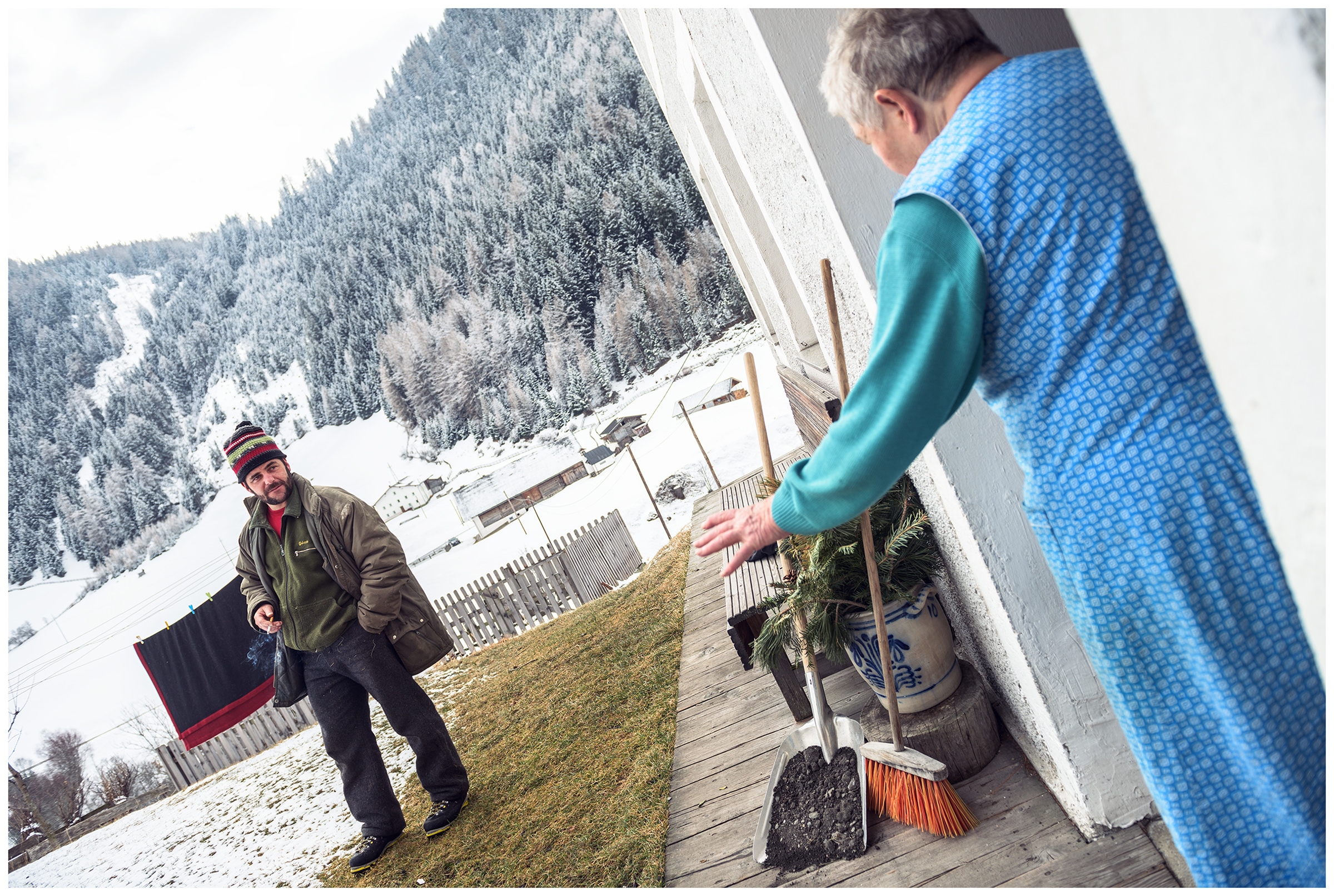 Valsertal, Wipptal, North Tyrol, Austria. A farmer smokes after hay drawing and talks to a woman for whom the hay was delivered.