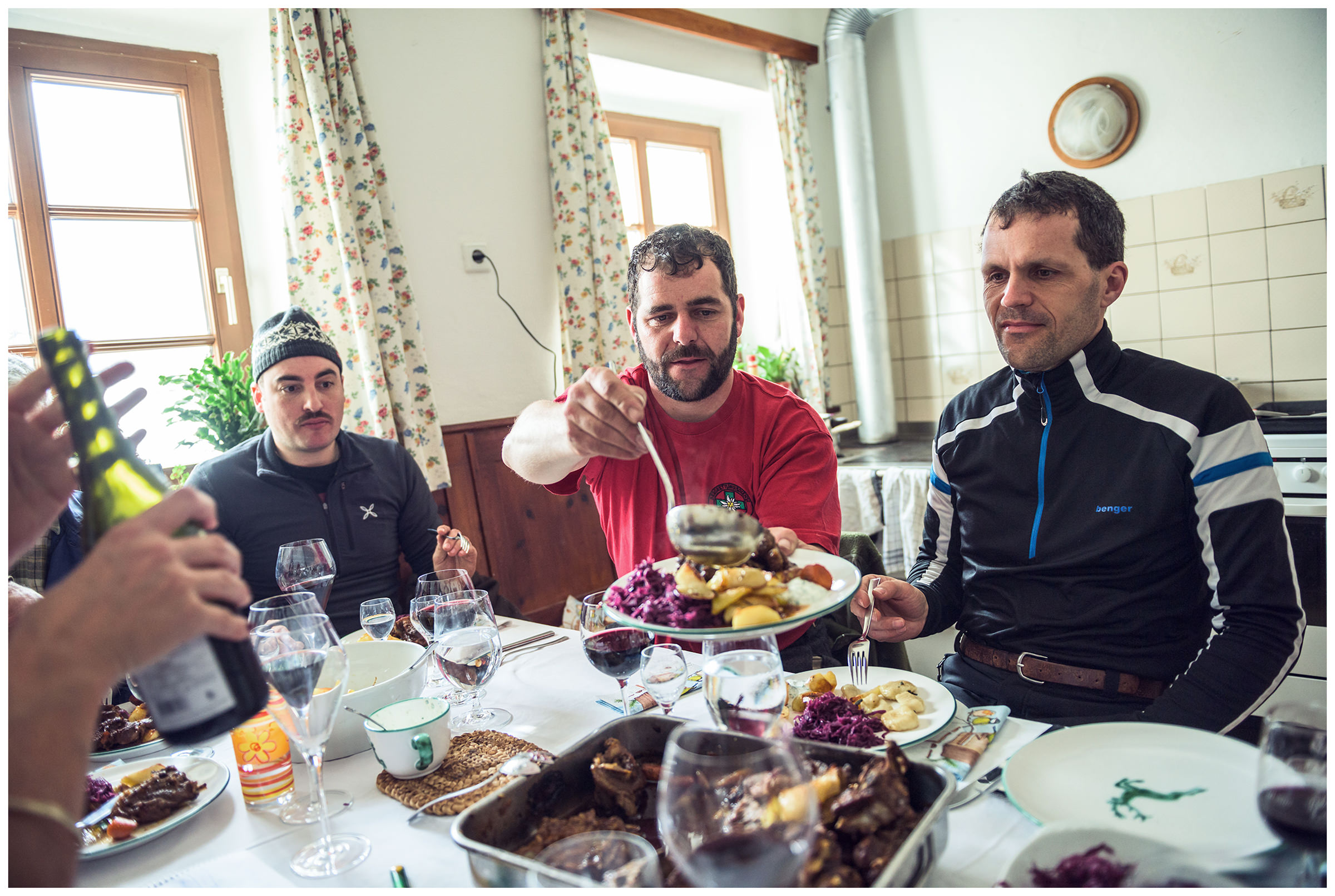 Valsertal, Wipptal, North Tyrol, Austria. A farmer sits at the table and eats with the woman for whom the hay was delivered after the hay has been pulled.