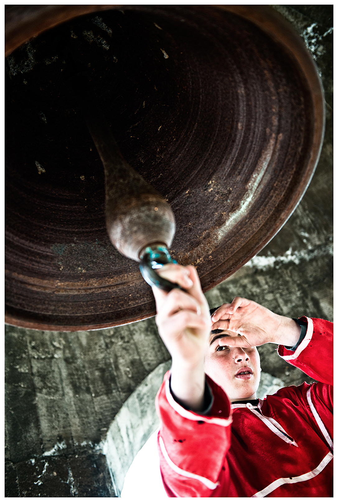 Imeretien, Georgien. Ein Junge im kirchlichen Gewand läutet in eine Glocke in einem Kloster.