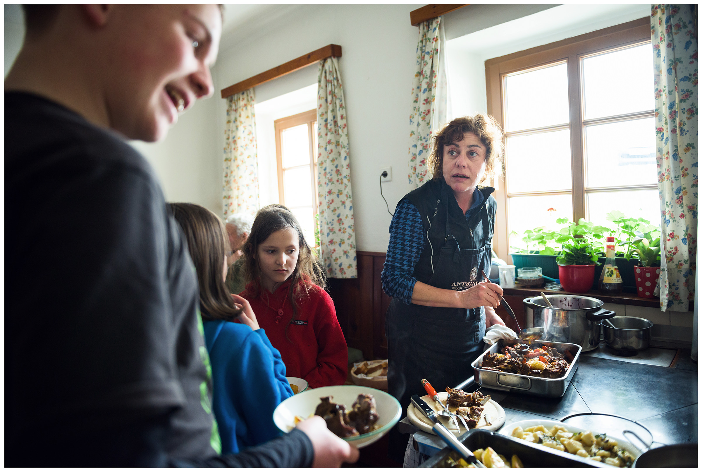 Valsertal, Wipptal, North Tyrol, Austria. A farmer puts the food in the children's plates.