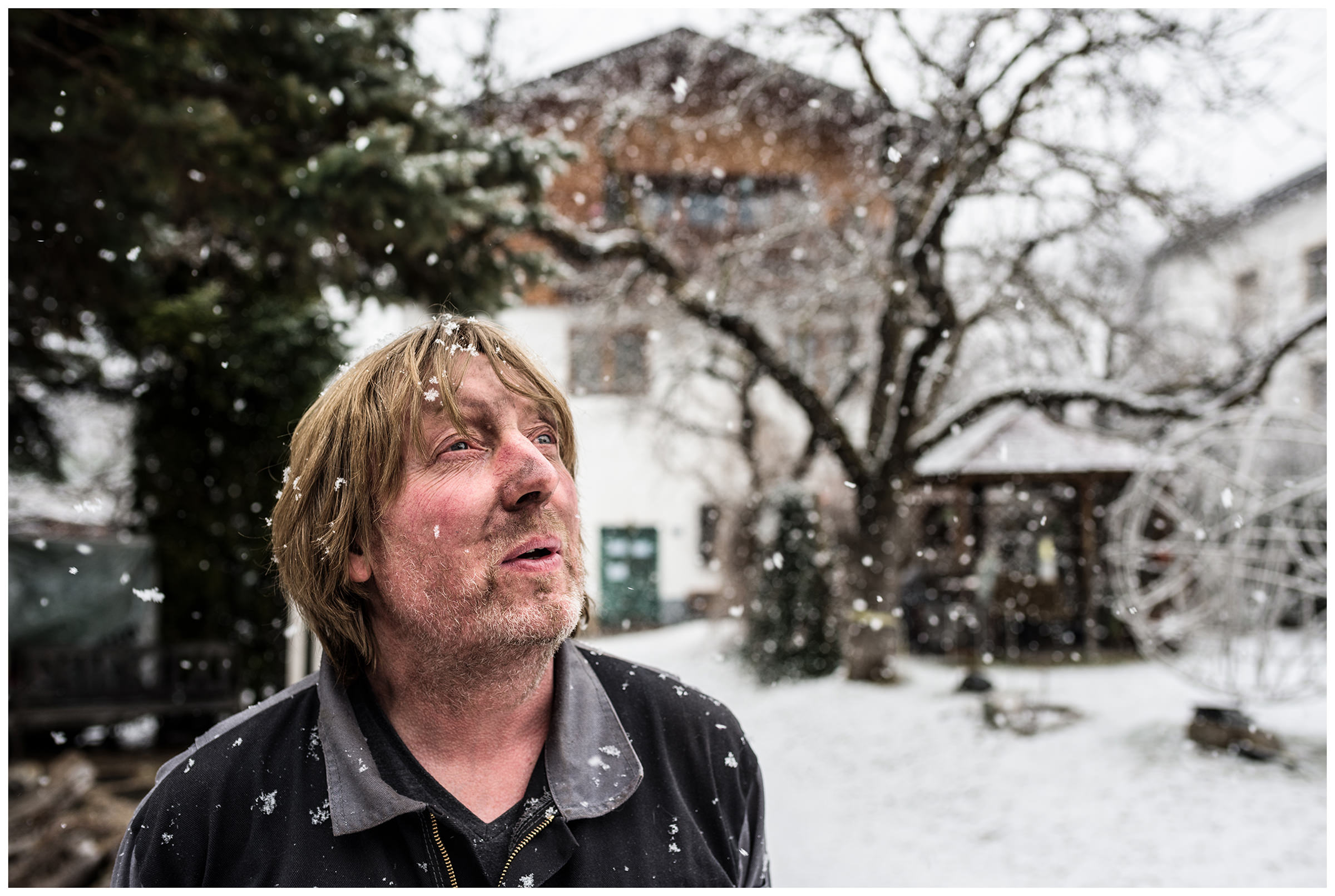 Wipptal, North Tyrol, Austria. A blacksmith stands in the yard in front of his blacksmith's shop in the snow.