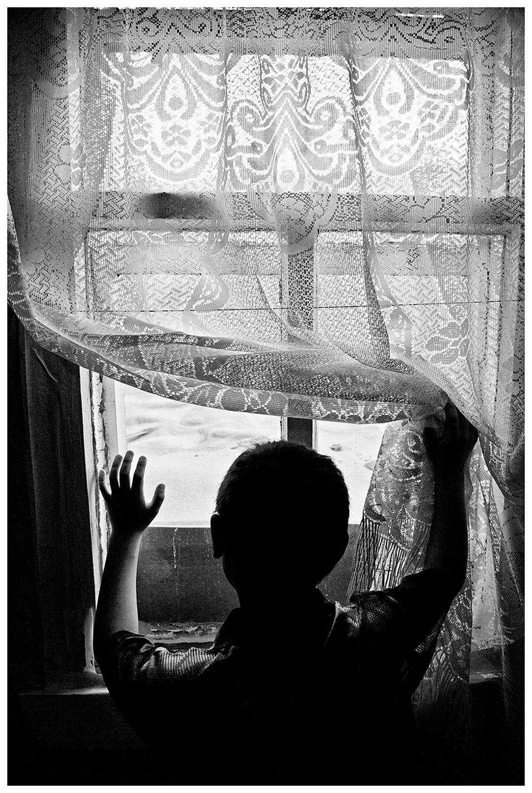 Shoyna village, Russia. A boy is standing in front of a window.