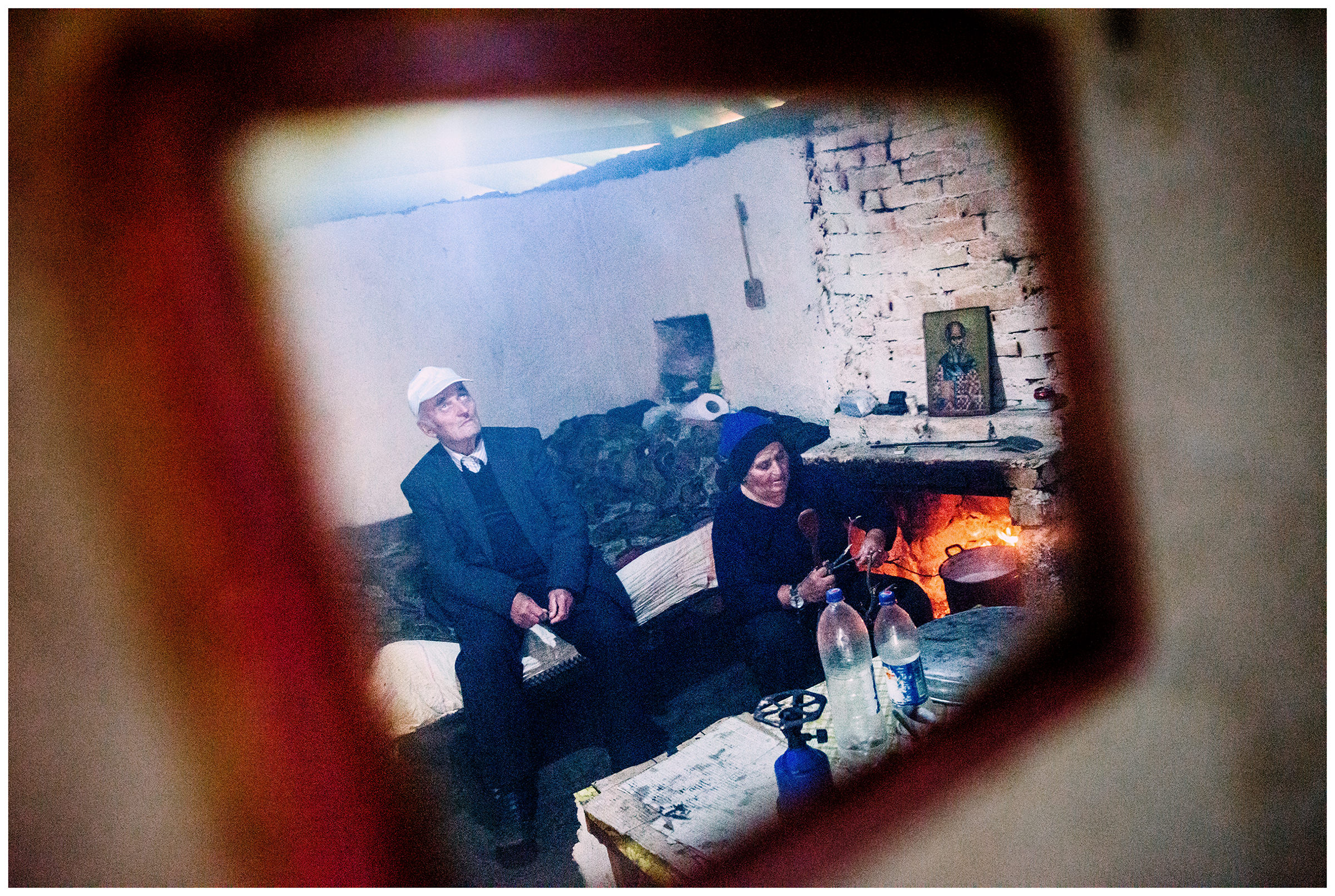 Albania, Lugu i Kokoshe. An old man and his wife are reflected in a mirror hanging on the wall of their shepherd's hut.