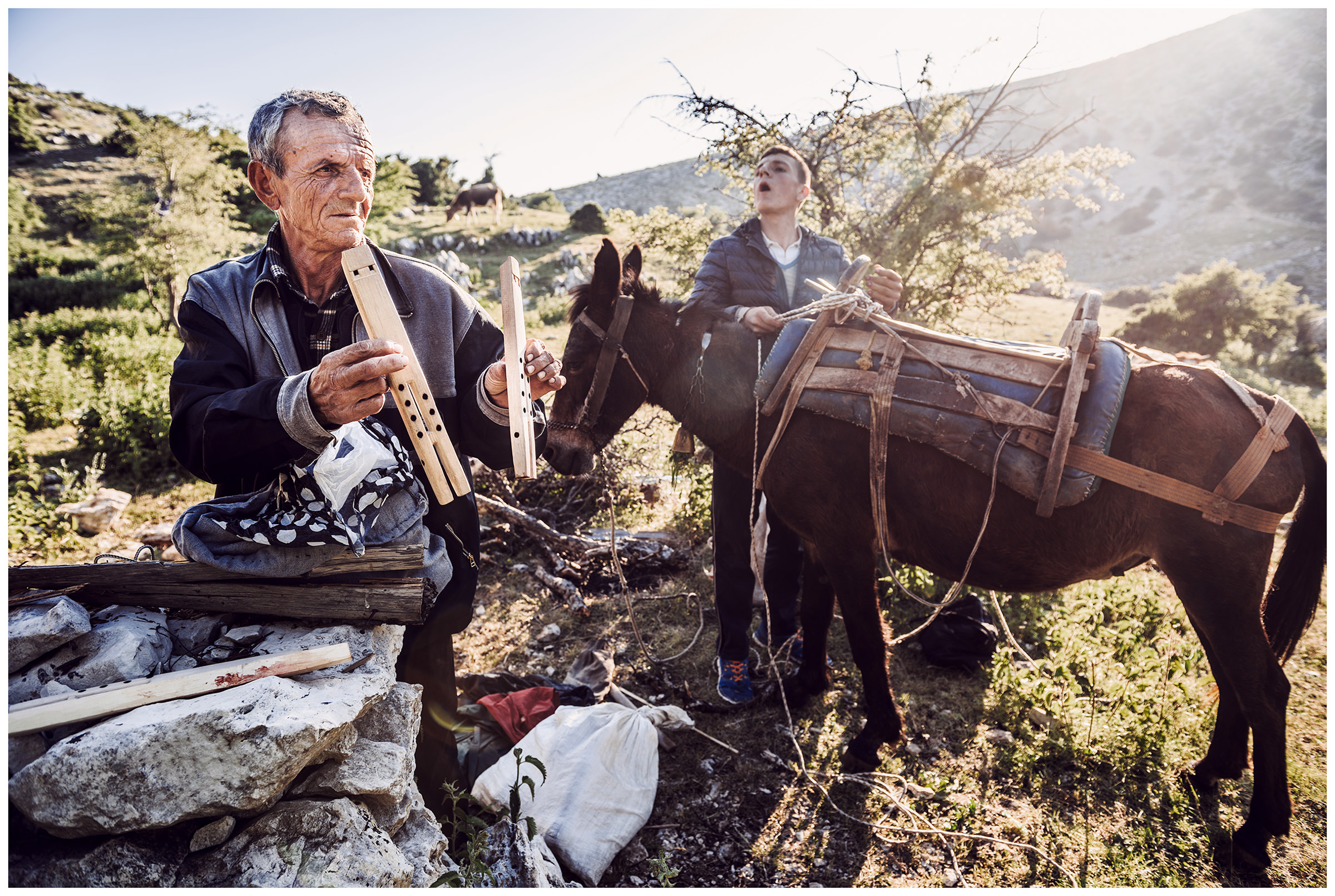 Albania, Llogora National Park. A shepherd binds his mule, while his uncle shows the floats he has made.