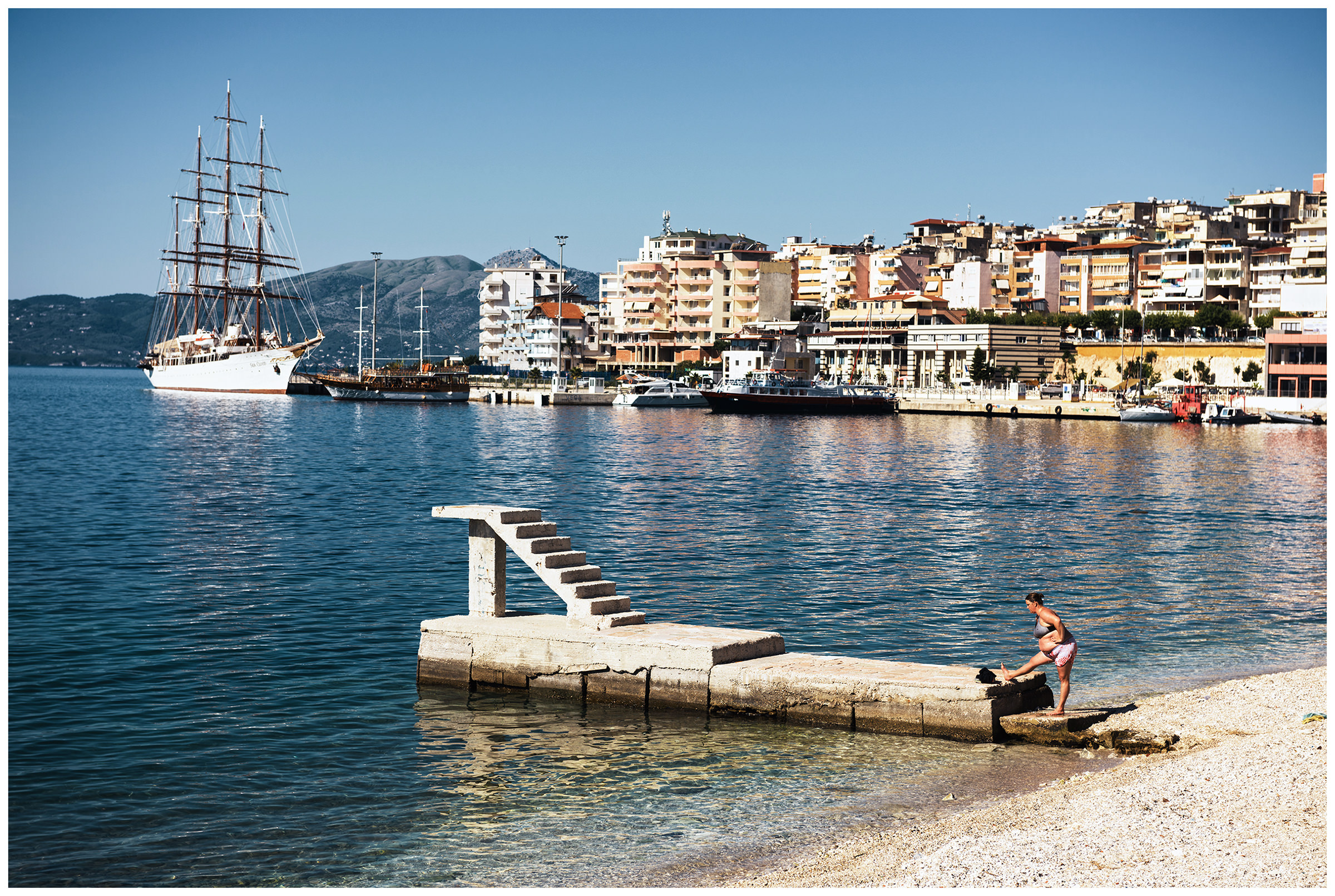 Albania, Saranda. A woman is doing stretching exercises on the beach of Saranda.