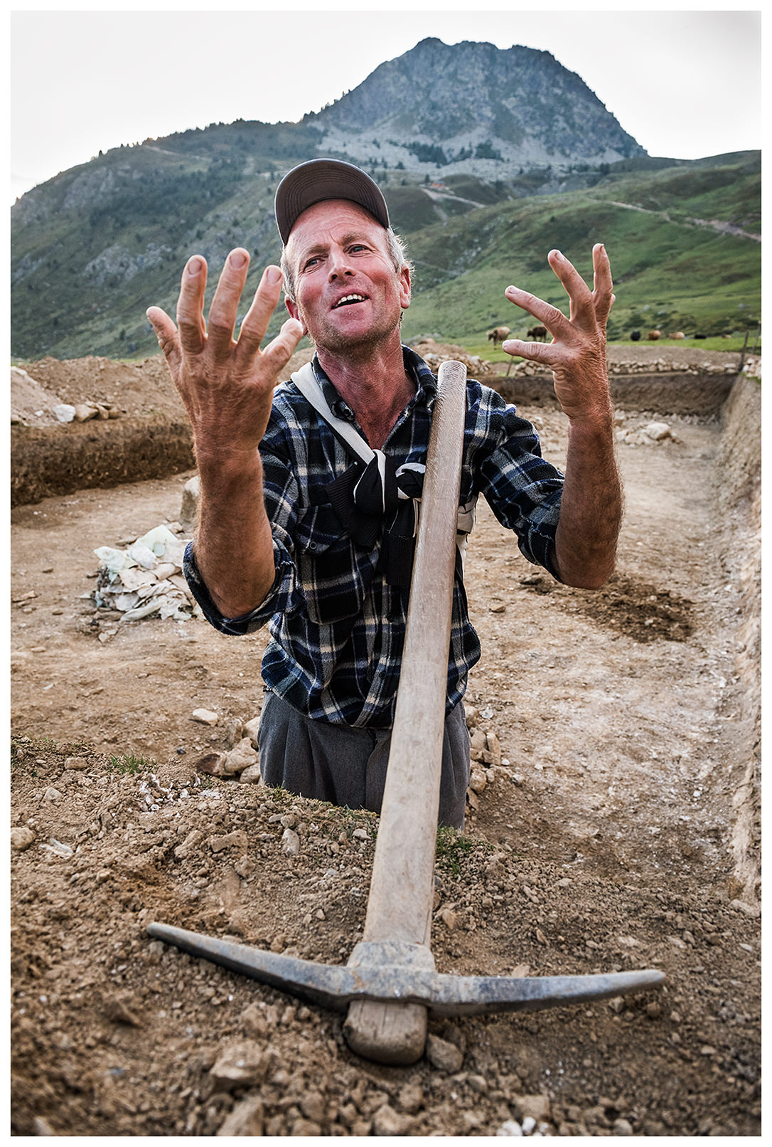 Doberdol, Albania. A man stands with a pickaxe in a pit not far from his house. The man plans to build a swimming pool for travellers.