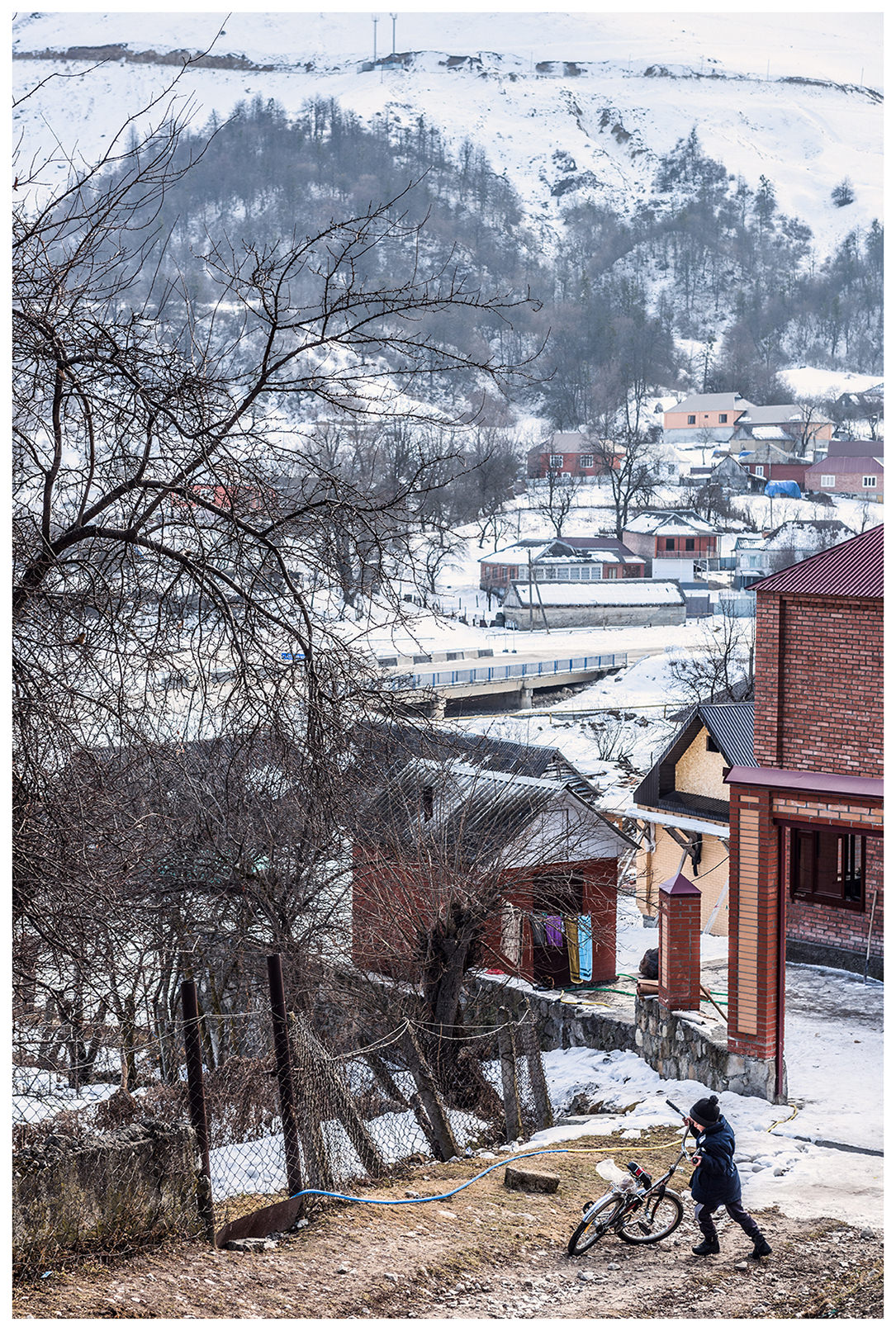 Harachoj village, Chechnya, Russia. A boy raises his bicycle in front of his house.