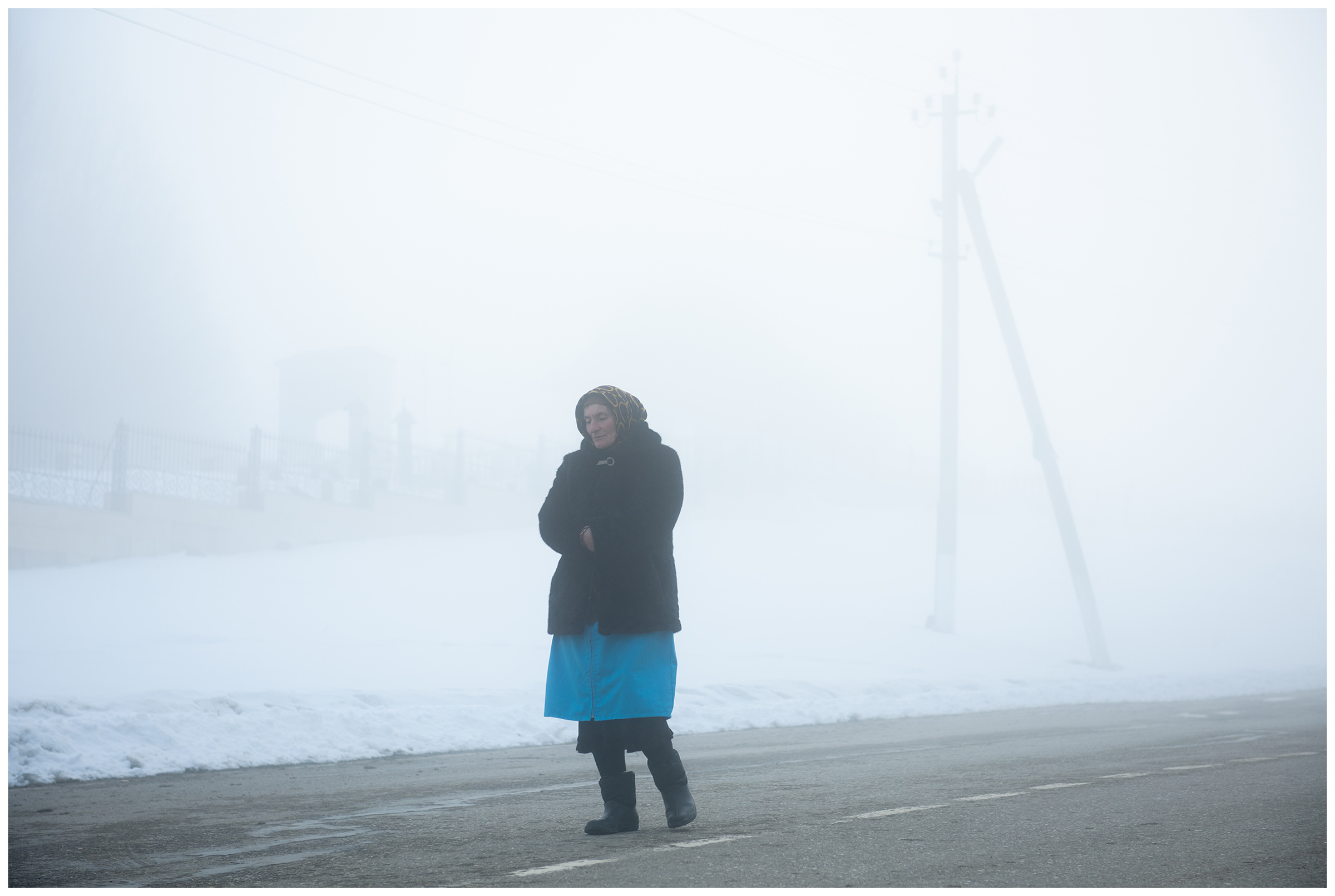 Village Perwomayskoye, Chechnya, Russia. A grave keeper is standing in the fog on the street in front of a Muslim cemetery.