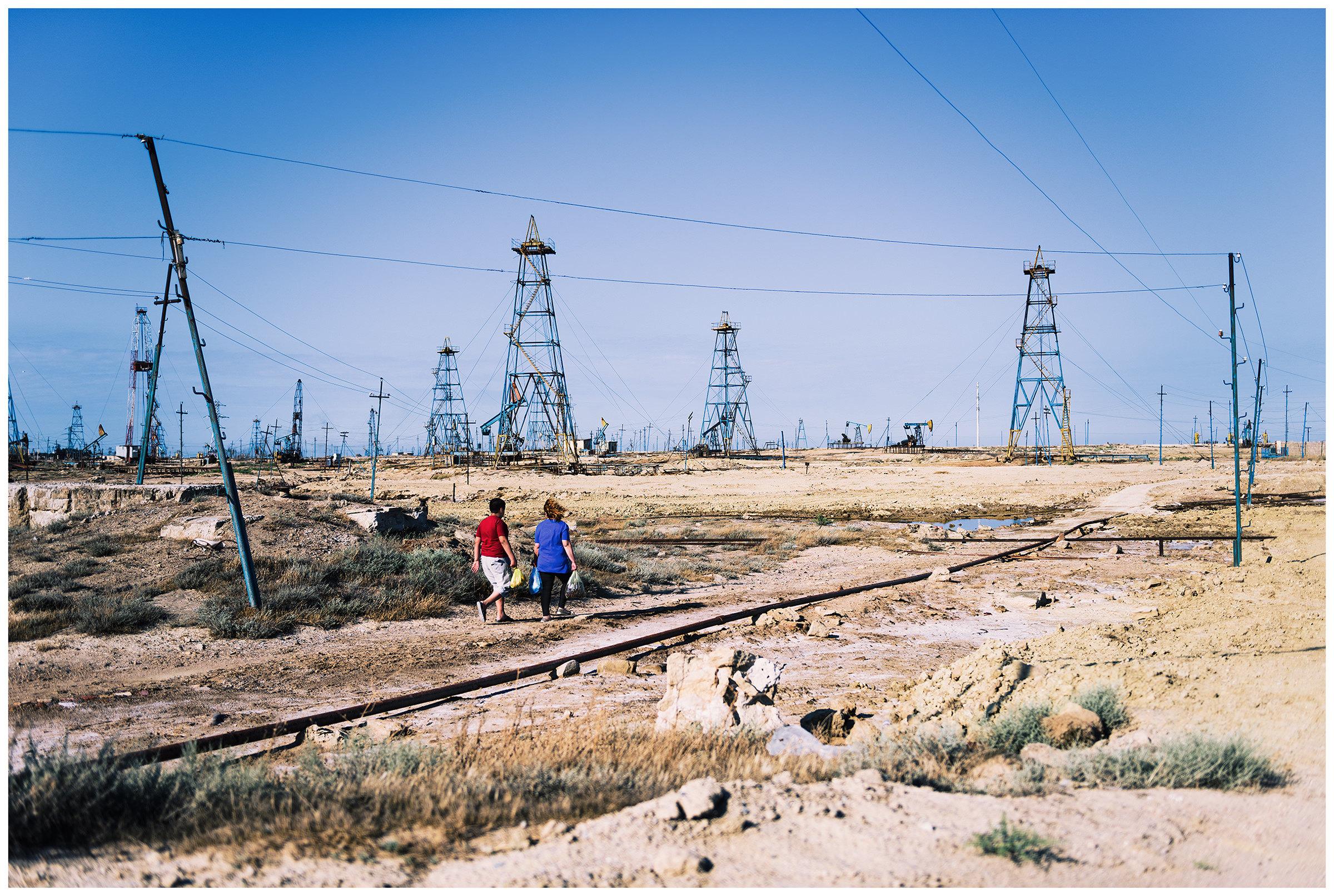 Azerbaijan, Surchany. A woman with a boy walking through the oil fields.