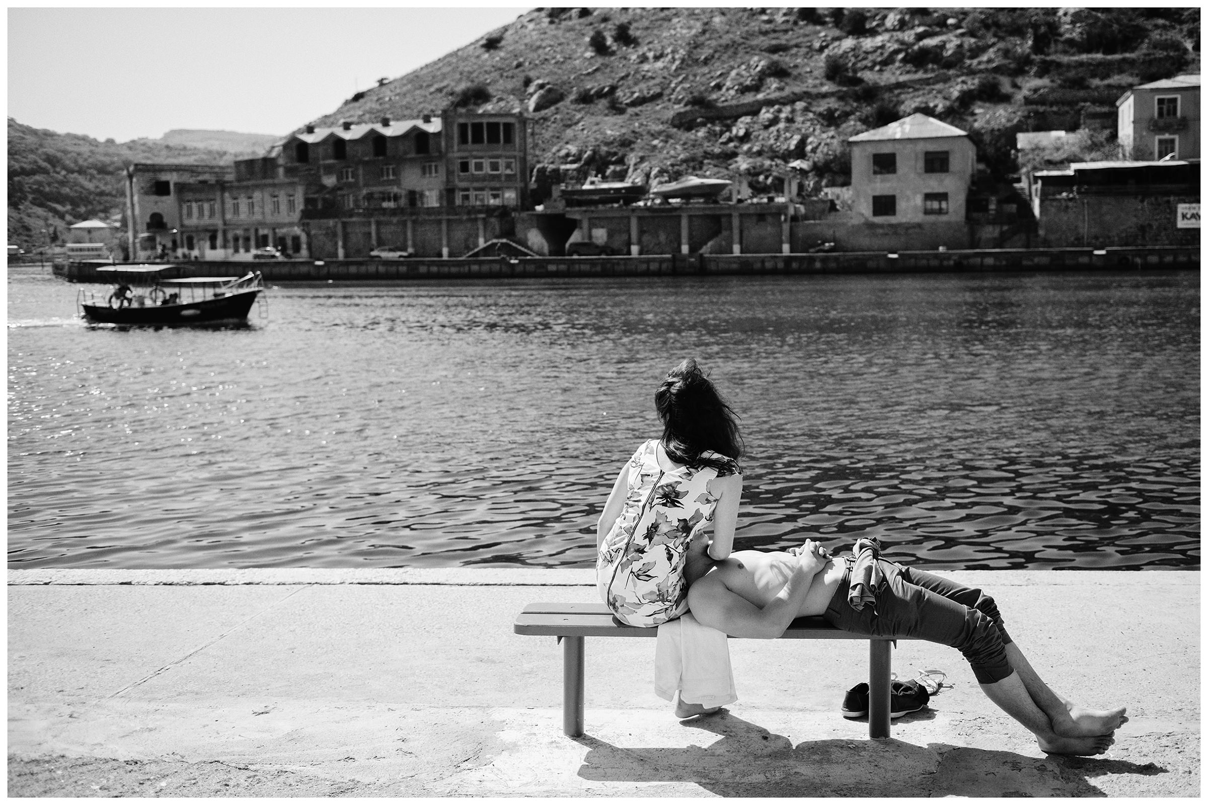 Balaklava, the Crimea. A couple is sitting on a bench on the shore of Balaklava Bay.