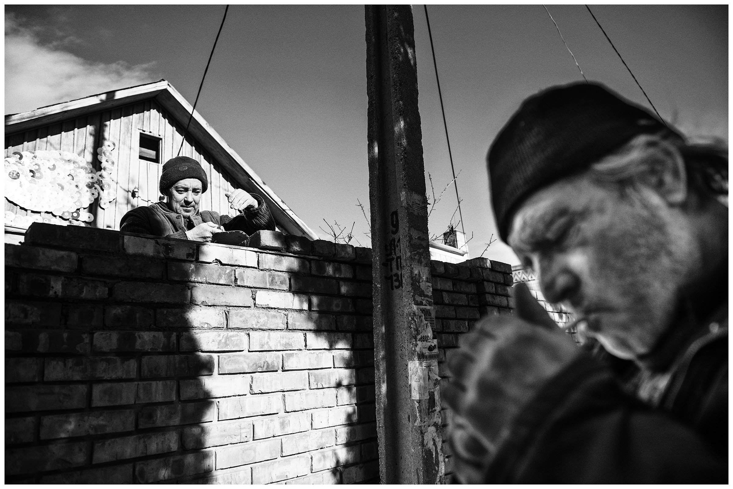 village Morskoye, Crimea. Two men build a wall around the house.