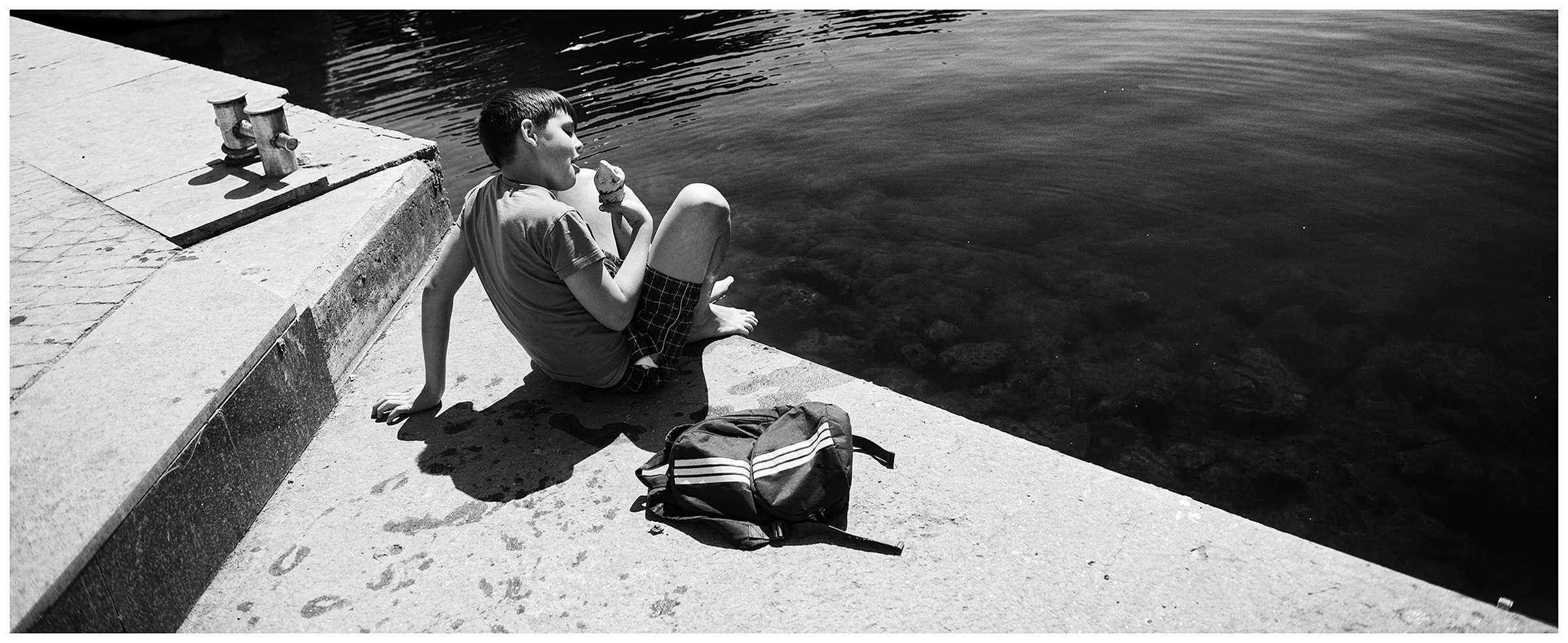 Balaklava, the Crimea. A boy eating ice cream on the shore of Balaklava Bay.