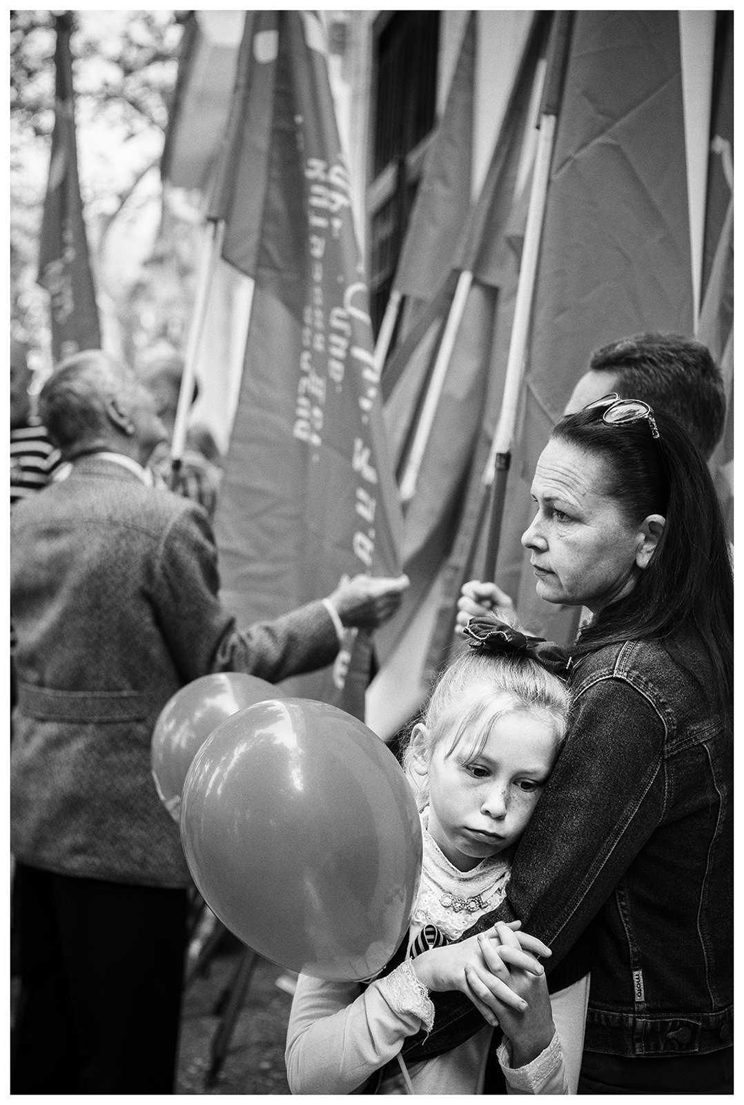 Sevastopol, the Crimea. A girl with balloons and the participants of the military parade stand at the roadside. The military parade is taking place on the occasion of the victory over Nazi Germany on May 9.