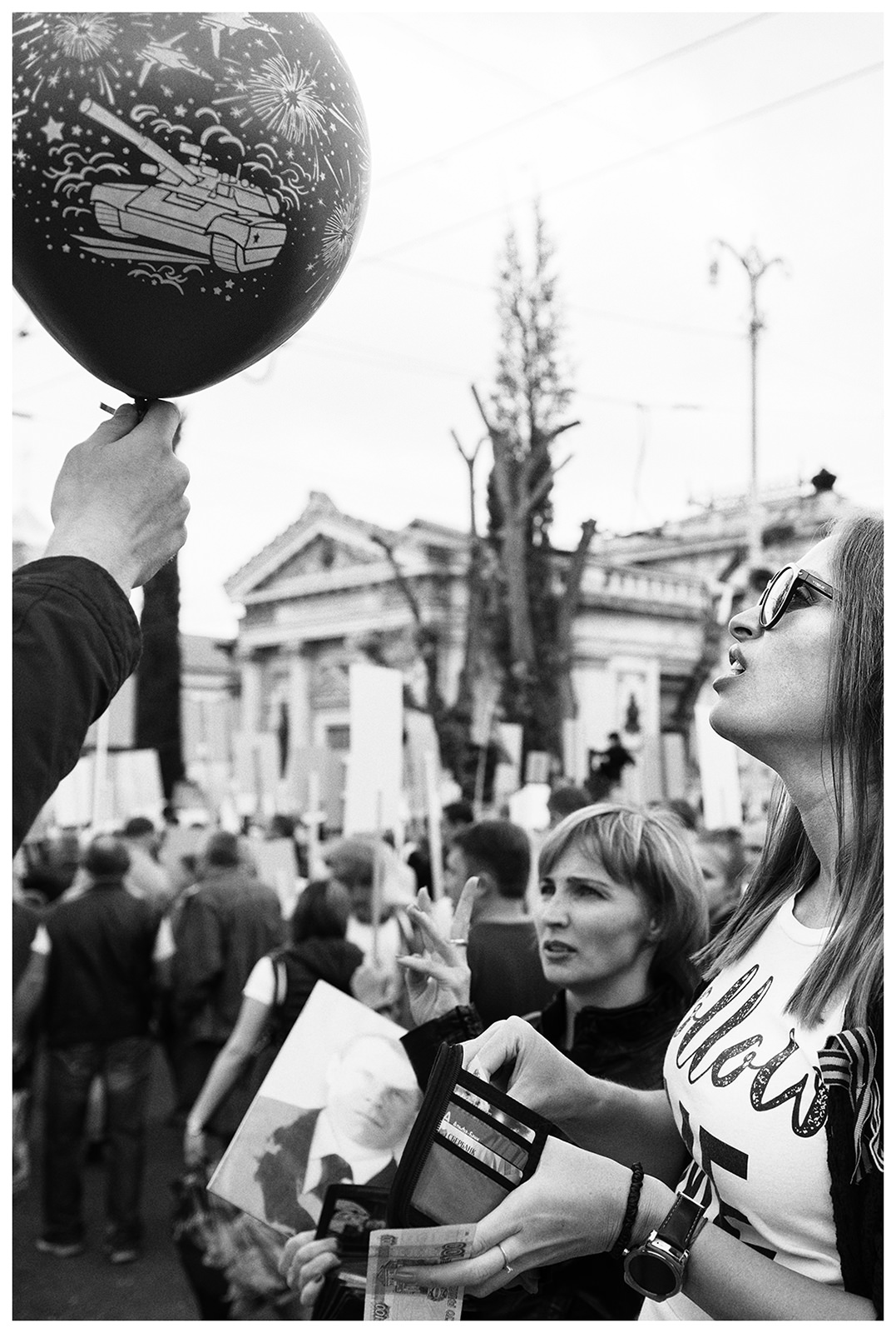 Sevastopol, the Crimea. A young woman buys a balloon with a tank on it at a military parade.