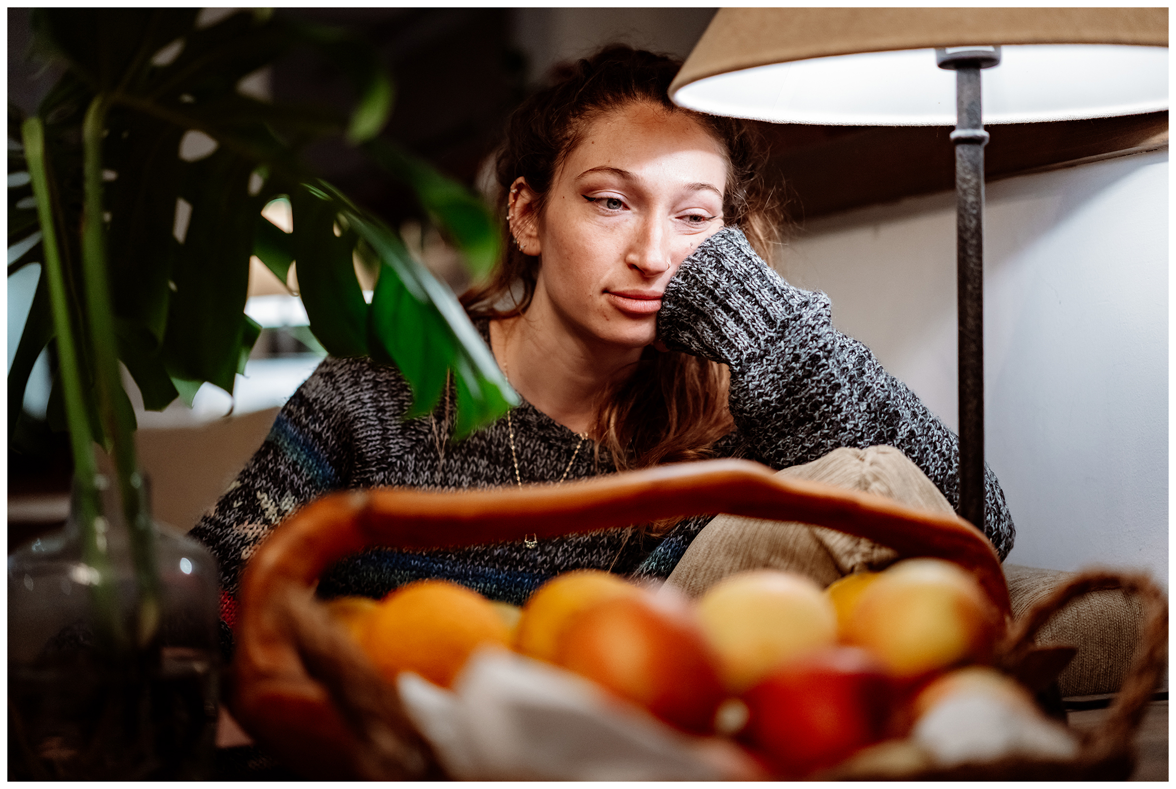 Miliou, Cyprus. A young woman sits at a table in lamplight with fruits in the foreground.