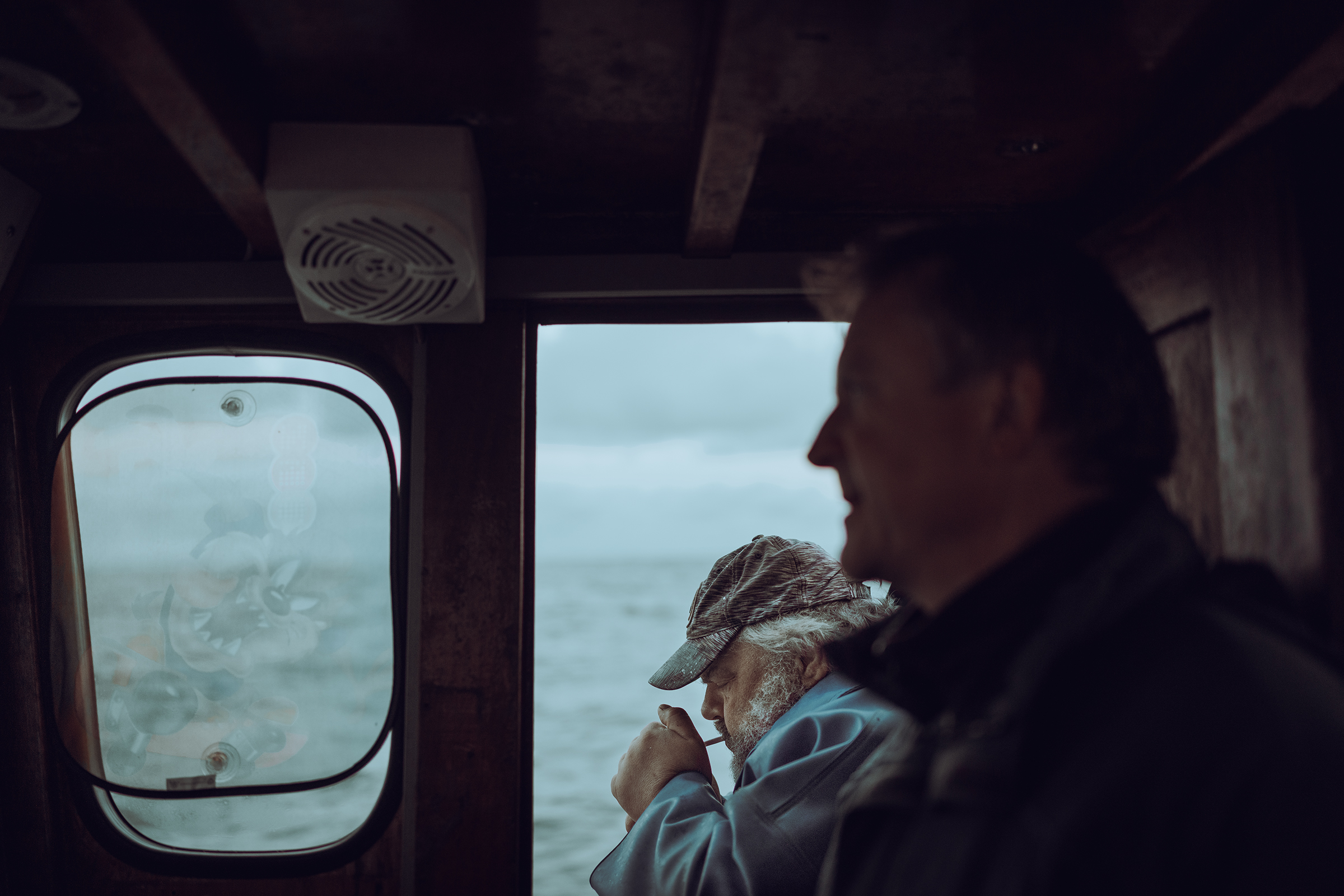 Two men look out from the cabin of a fishing boat onto the Baltic Sea near the coast of Latvia.